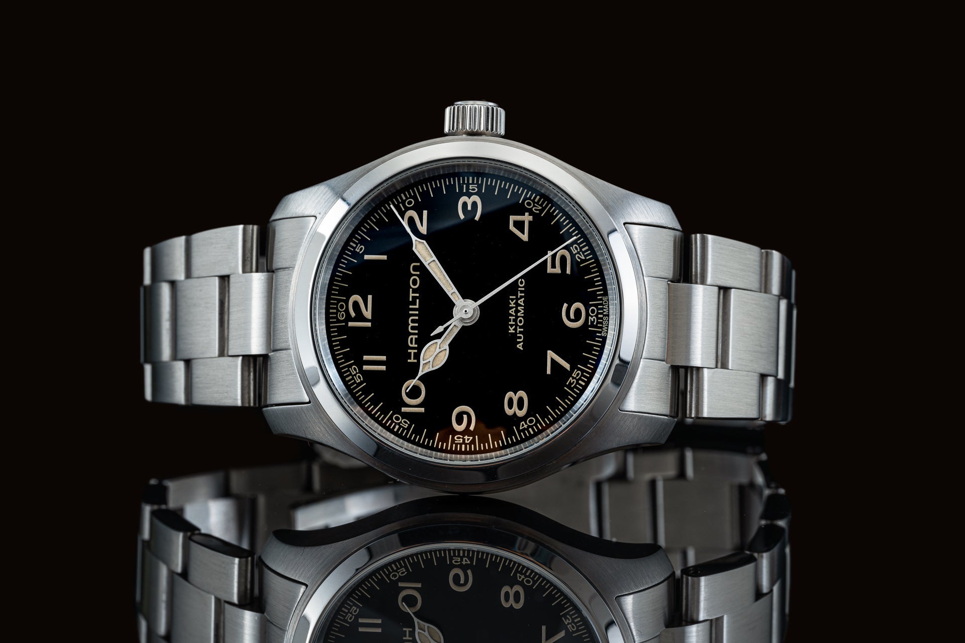 Hamilton Khaki automatic watch with stainless steel bracelet and black dial on reflective surface