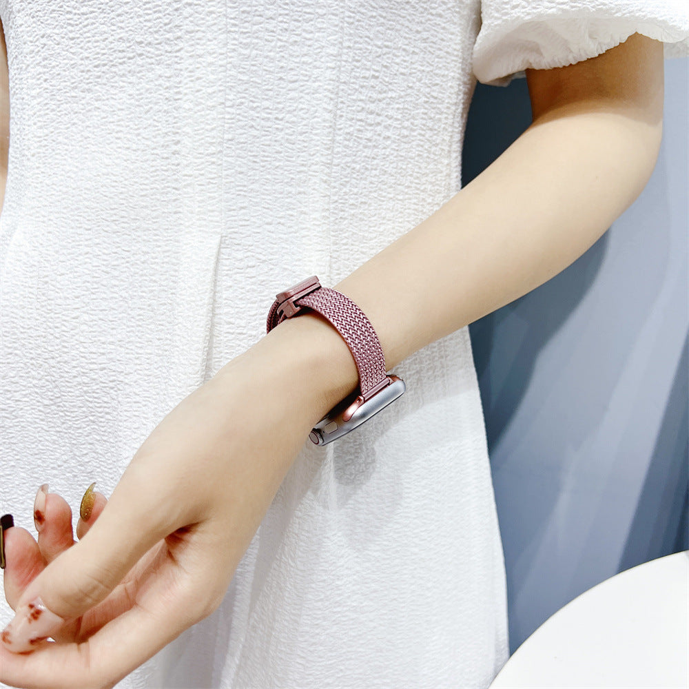 Rose gold herringbone mesh smartwatch band with magnetic clasp on woman's wrist wearing white sleeve