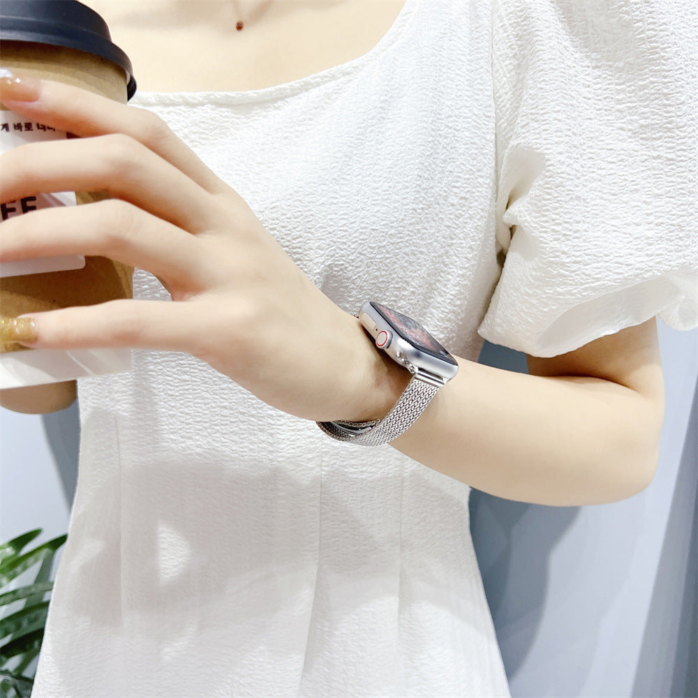 Woman wearing silver herringbone mesh bracelet on Apple Watch with white textured sweater and coffee cup