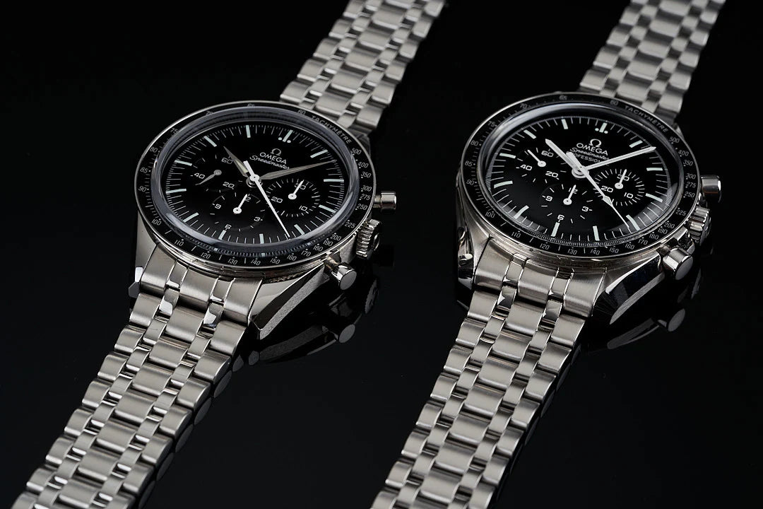 Omega Speedmaster chronograph watches with stainless steel bracelets and black dials on black background