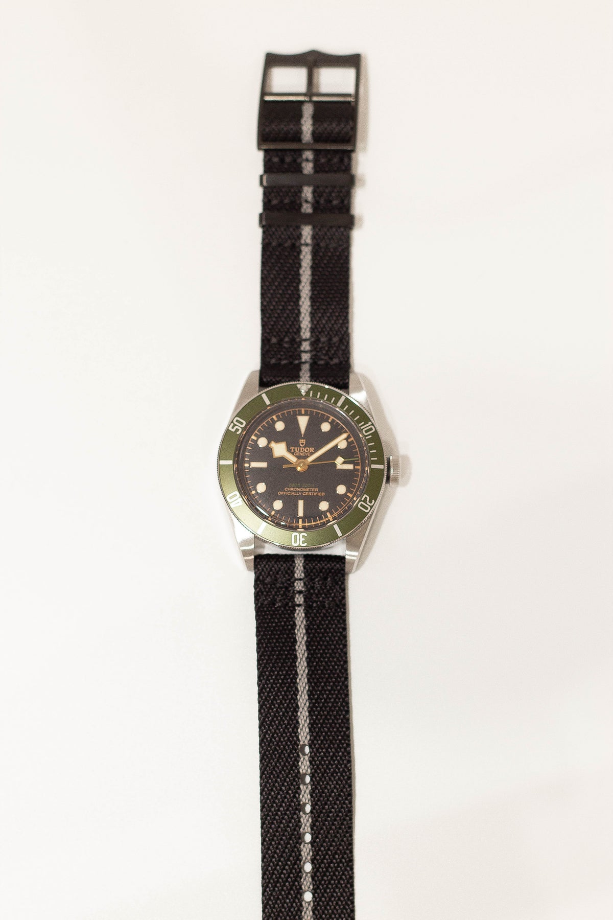 Tudor Black Bay dive watch with green bezel, black dial, steel case and black fabric strap with stripe detail