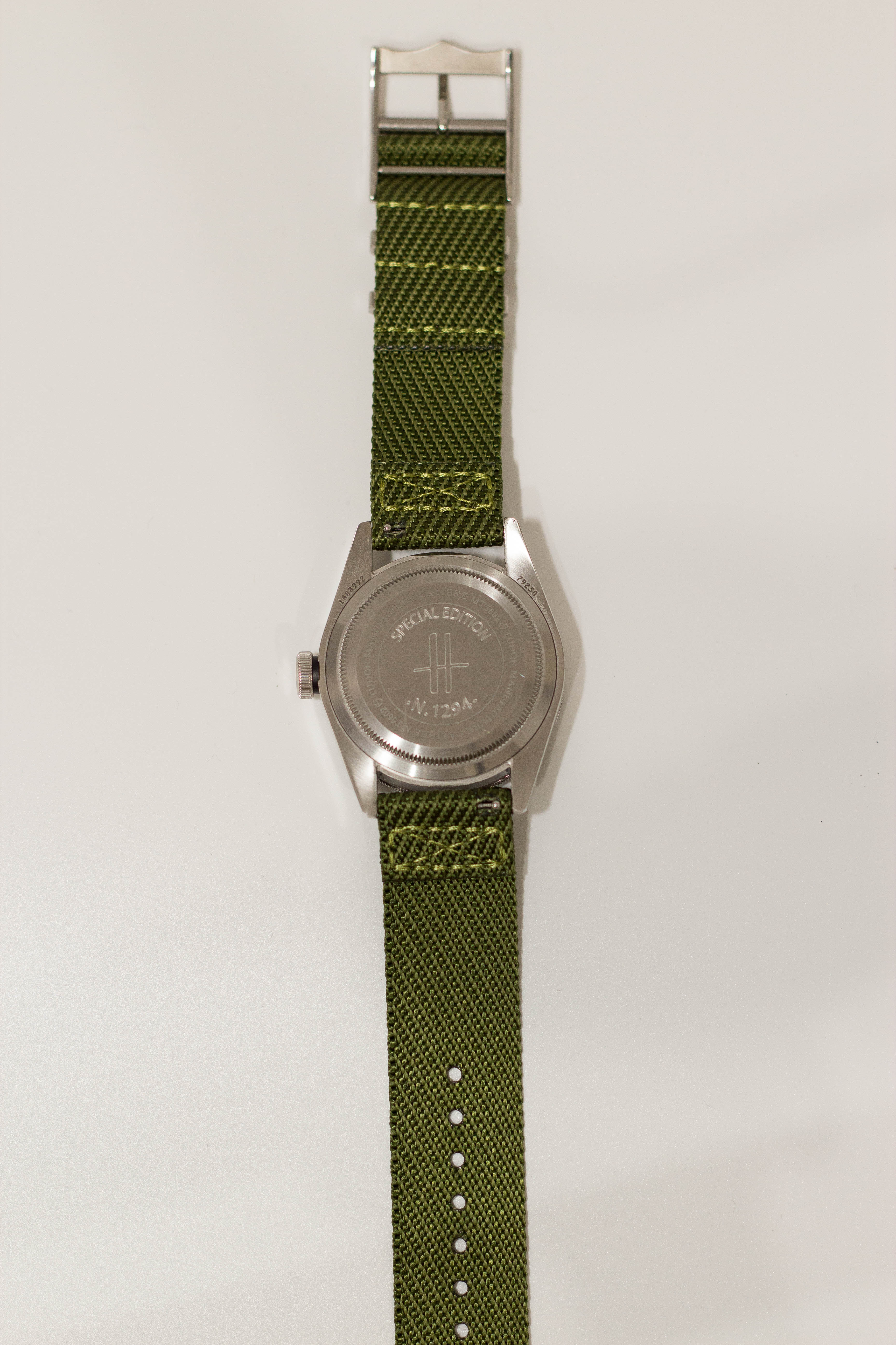 Military-style army green fabric watch band with silver buckle and hardware for Fitbit smartwatch