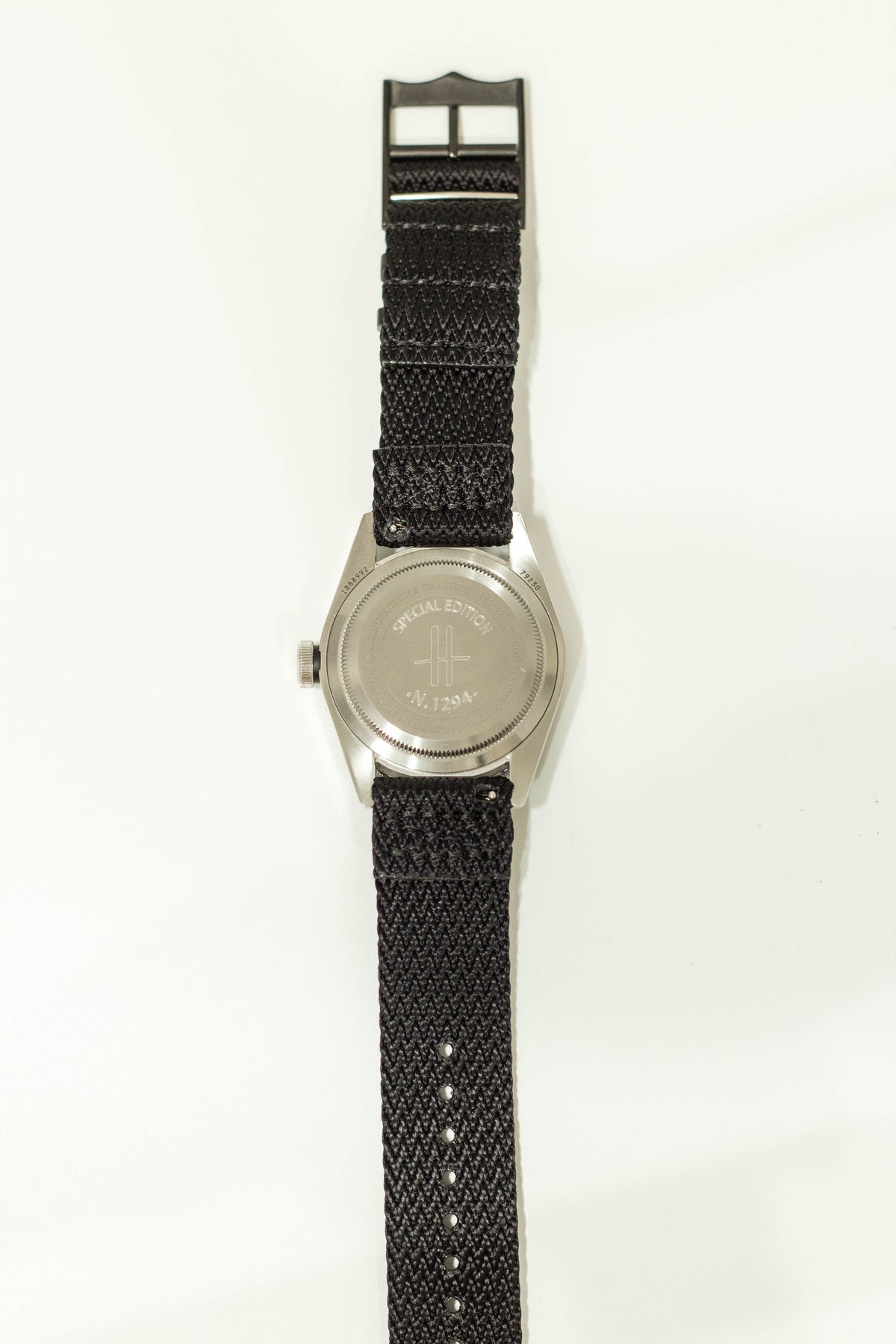 Silver military watch with black fabric strap and engraved case back, official edition timepiece with numbered serial