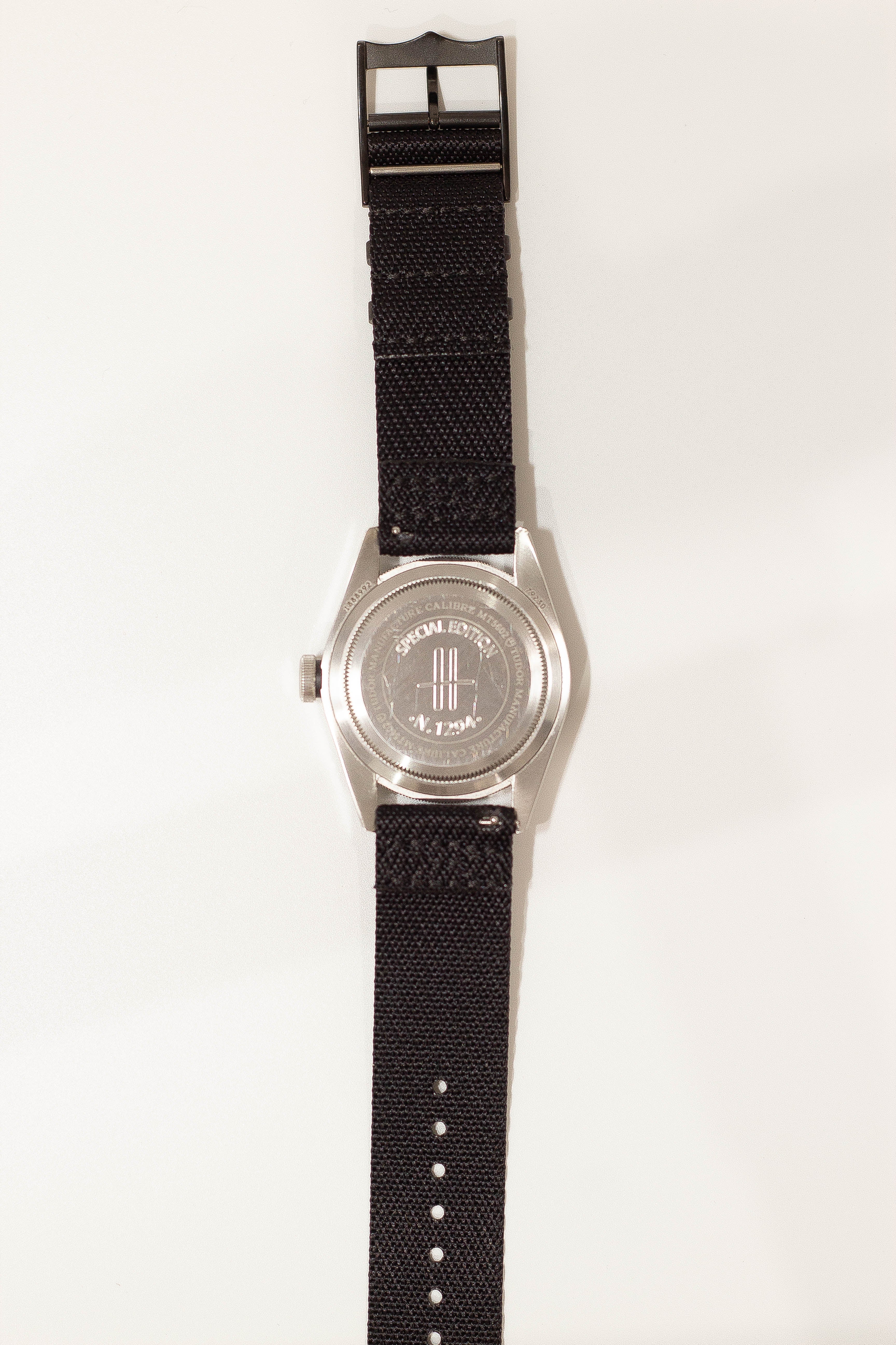 Stainless steel watch with black fabric strap and special edition caseback design