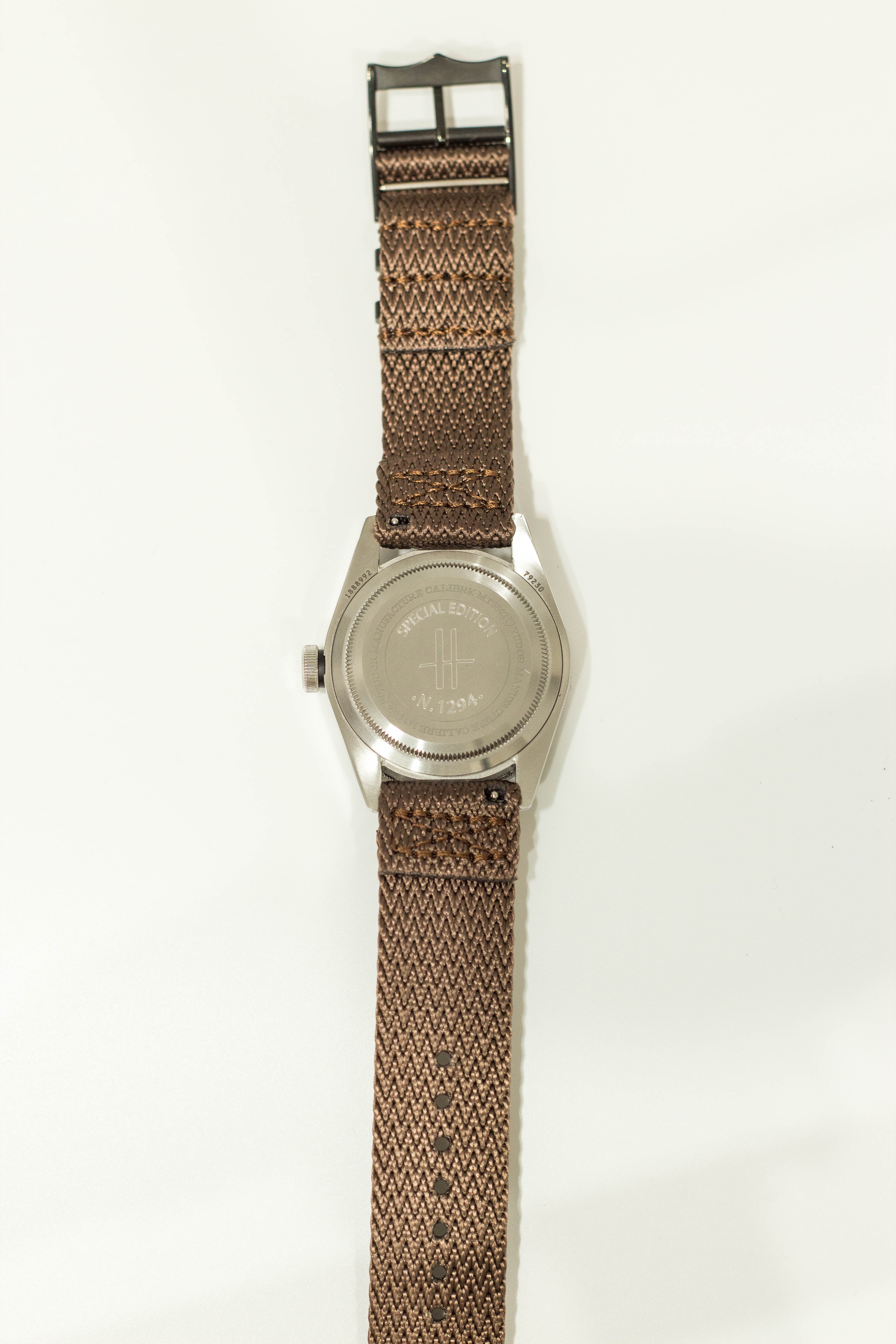 Stainless steel watch with brown woven military fabric strap, black hardware, and special edition engraved caseback