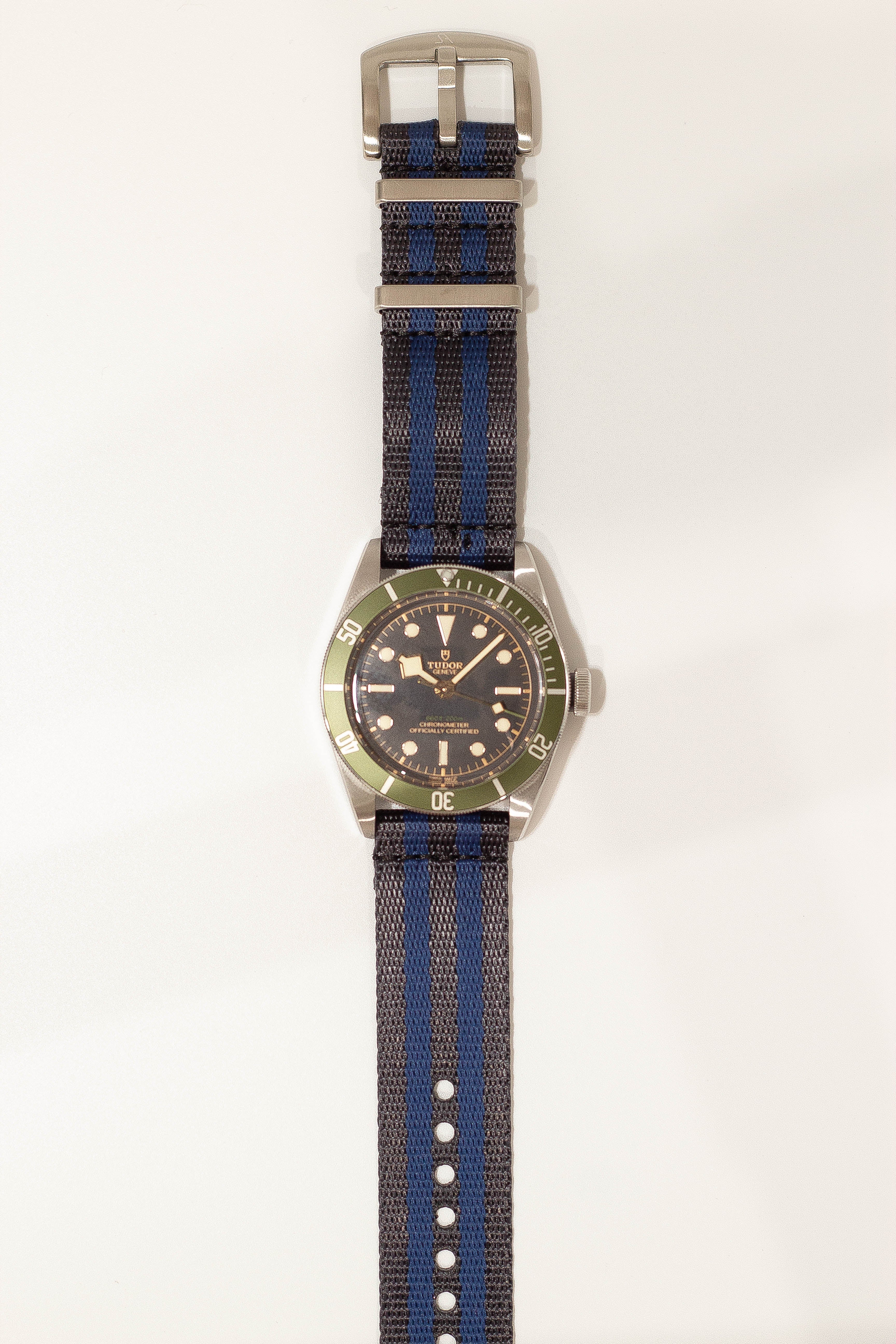 Tudor Black Bay diving watch with green bezel, bronze case, dark dial and blue striped fabric NATO strap
