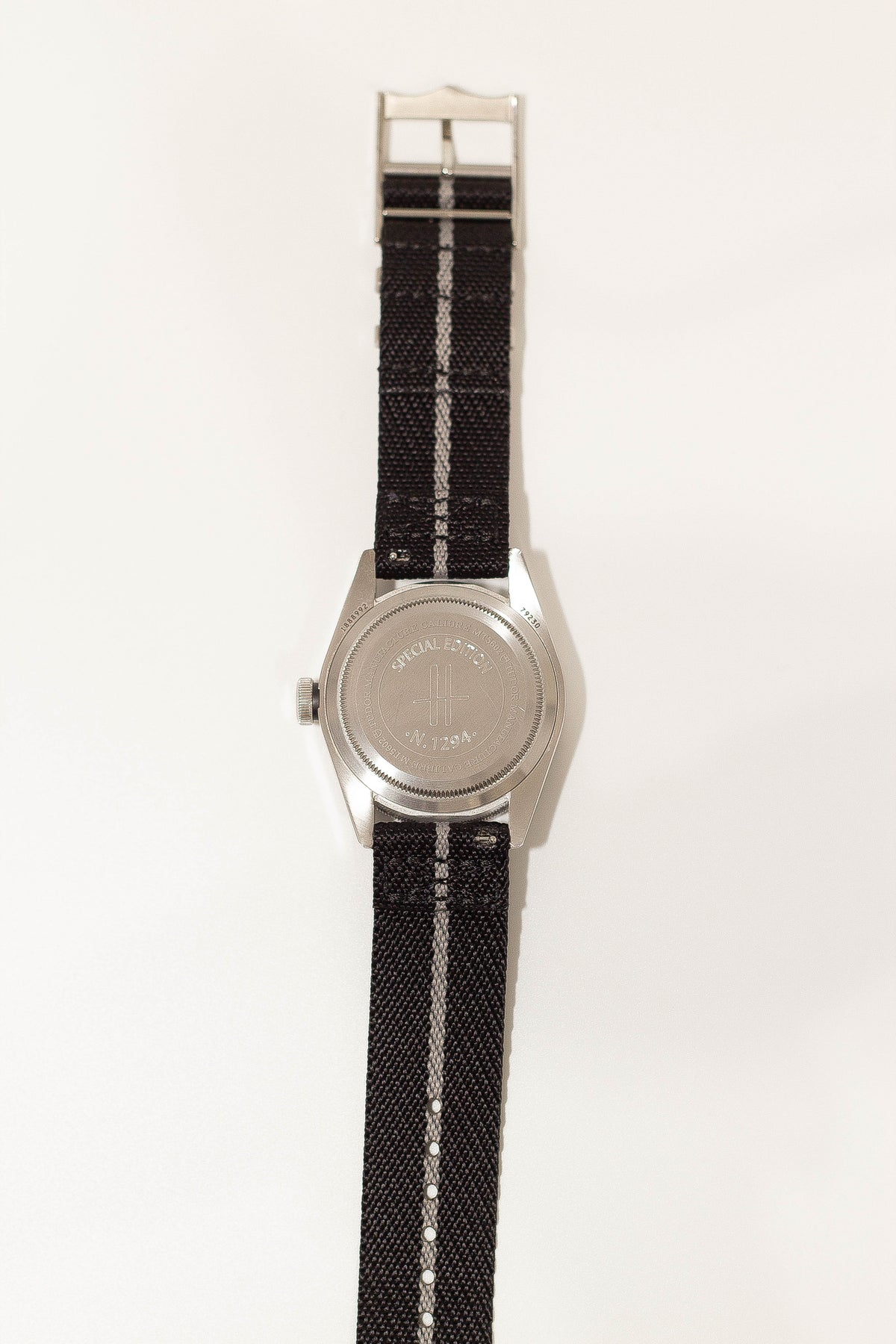 Silver watch with black and grey striped fabric strap and special edition case back detail