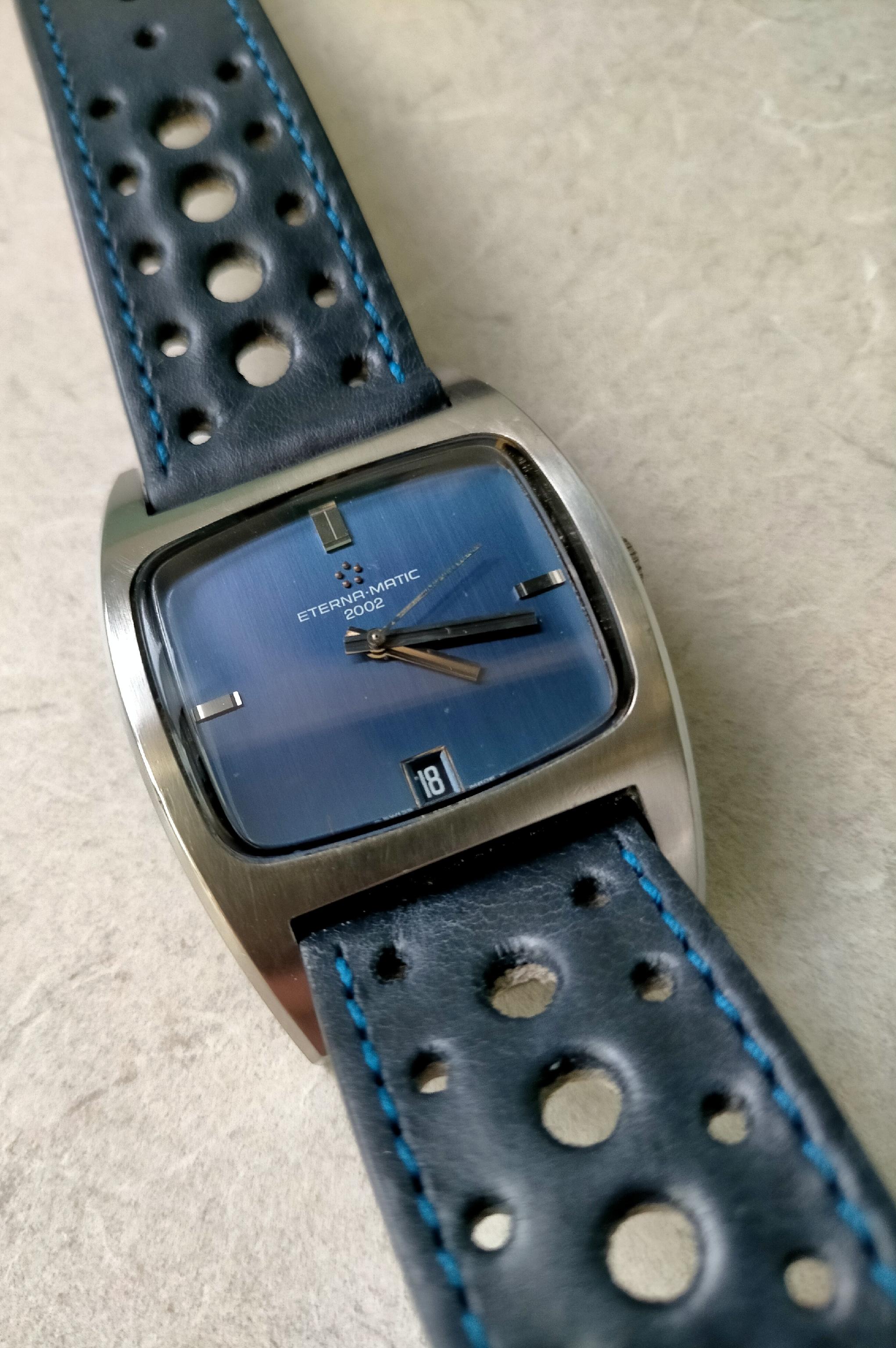 Eterna Matic 2002 automatic watch with blue dial and stainless steel case on perforated navy blue leather strap