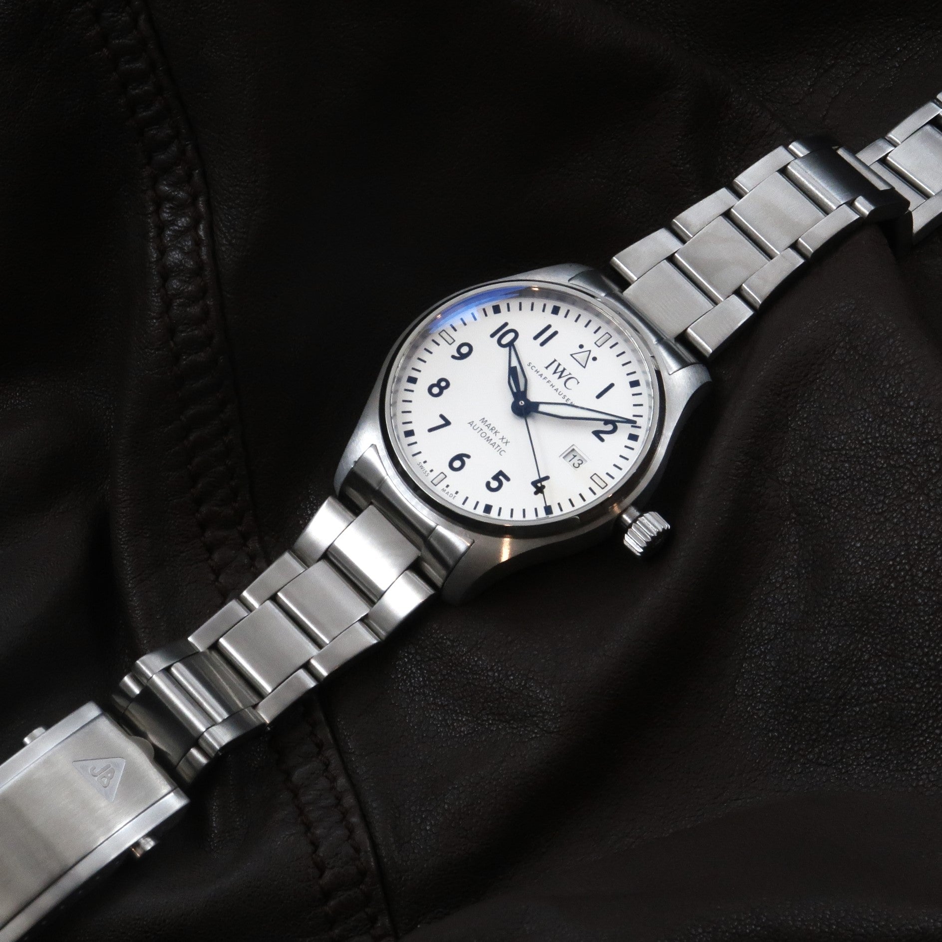 IWC Mark XX stainless steel automatic pilot watch with white dial and metal bracelet on black leather background