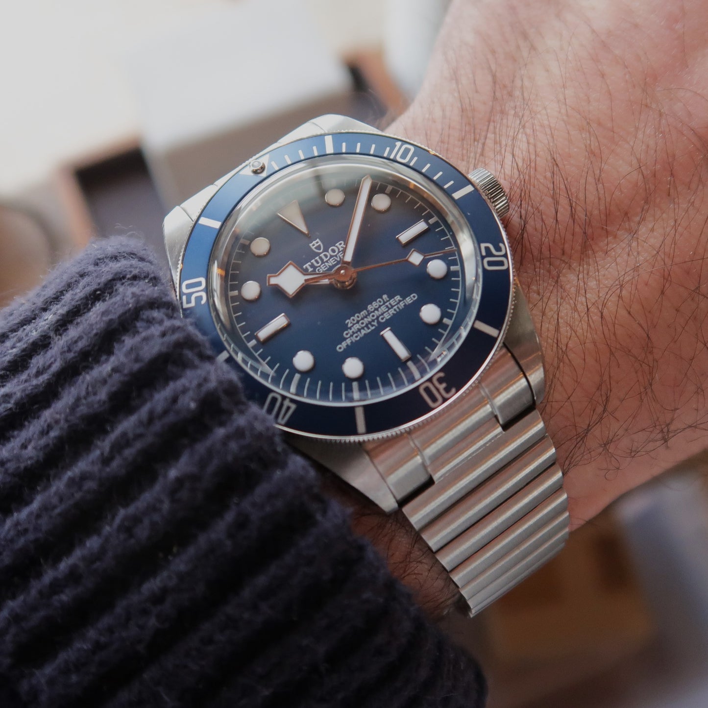 Tudor Black Bay 58 automatic dive watch with steel Forstner barrel bracelet on wrist wearing blue sweater