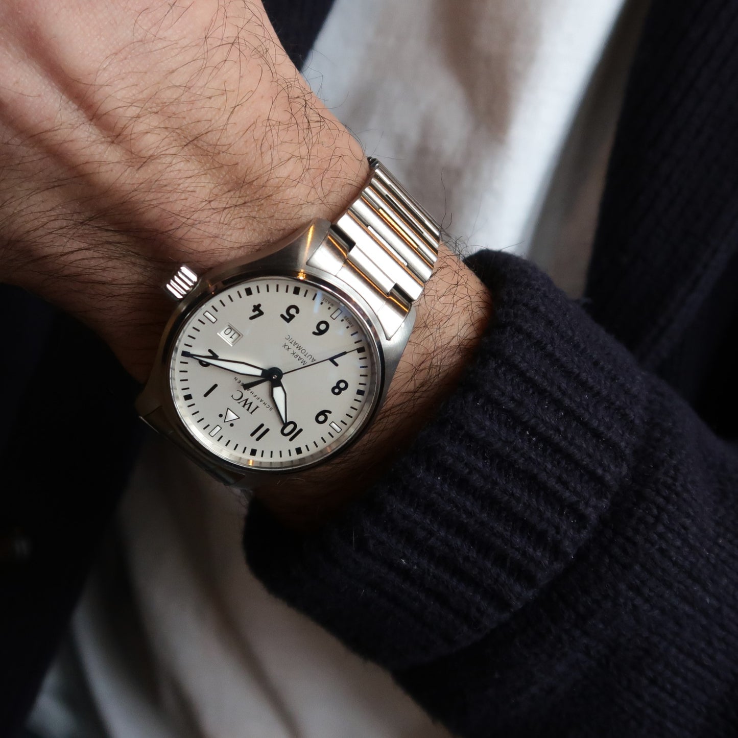 Men's stainless steel pilot watch with cream dial and barrel bracelet worn on wrist with dark sweater