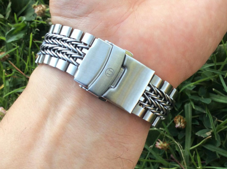 Silver stainless steel straight end bracelet with razor-wire center links and solid end links worn on wrist outdoors