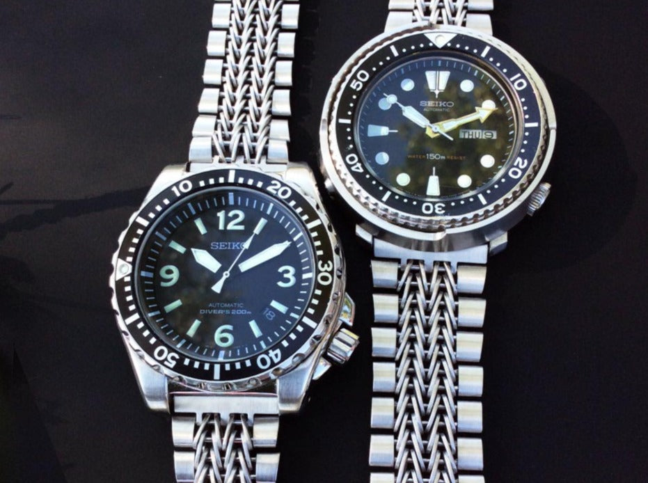 Two Seiko automatic diver watches with stainless steel razor-wire straight end bracelets on black background