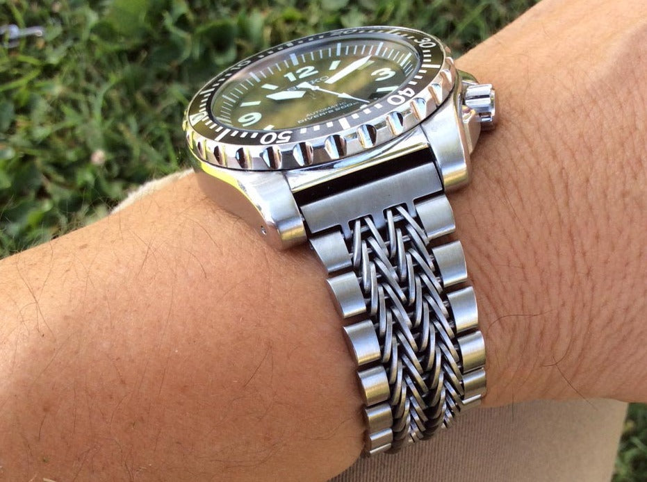 Two-tone stainless steel dive watch with razor-wire bracelet on wrist, showcasing textured metal link design and rotating bezel