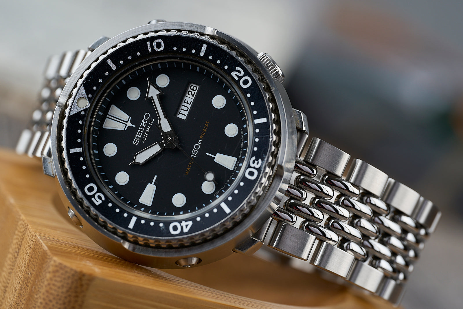 Seiko automatic dive watch with black dial, luminous indices, rotating bezel, and steel bracelet on wooden surface