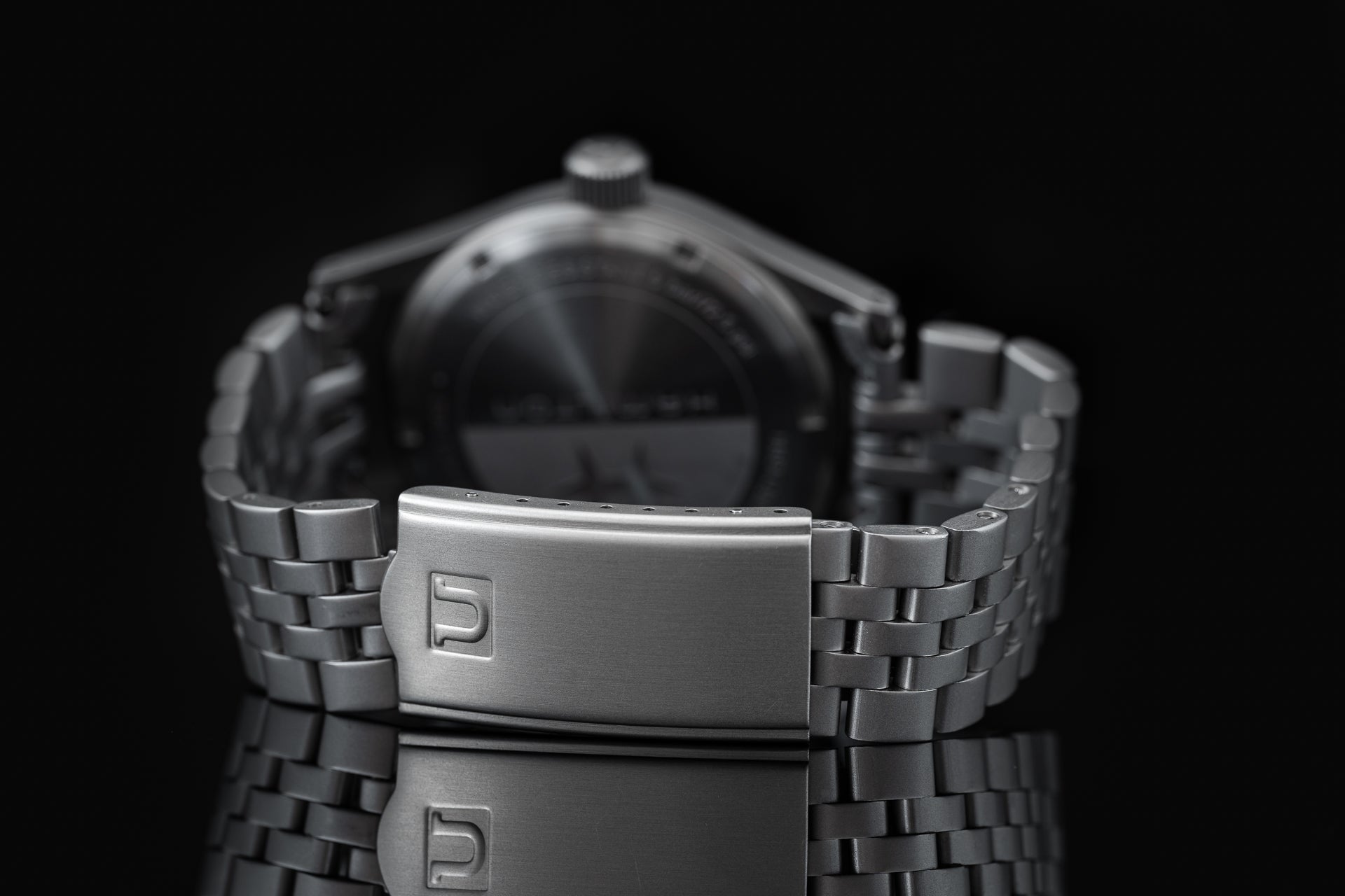 Stainless steel mechanical watch with metal bracelet and fold-over clasp displayed on black background