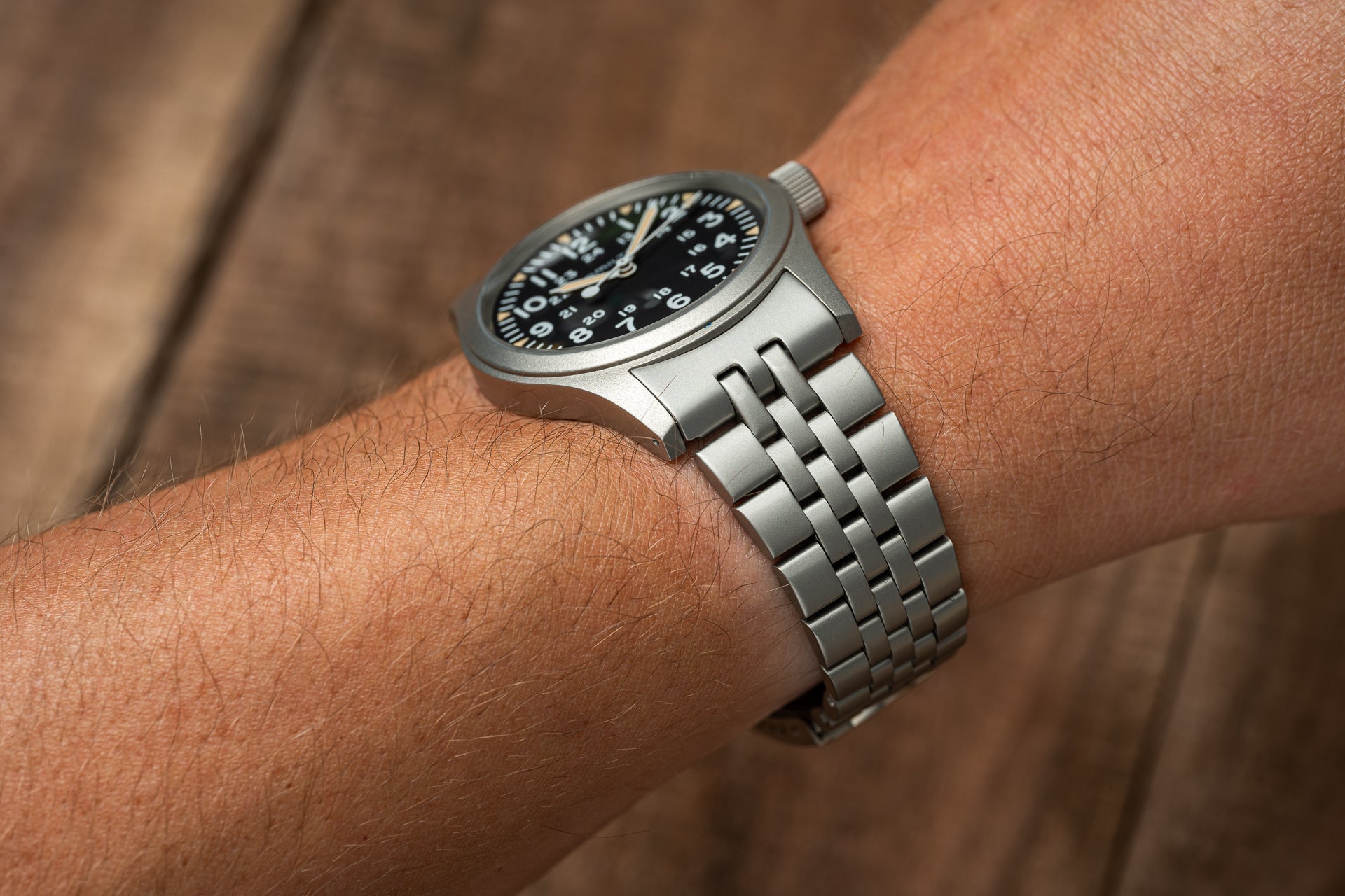 Stainless steel mechanical watch with black dial and linked metal bracelet worn on wrist