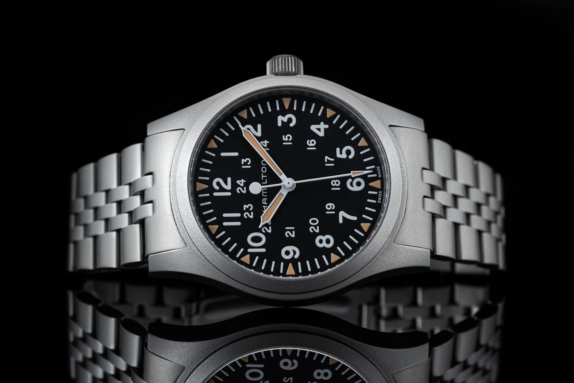 Stainless steel mechanical watch with black dial, Arabic numerals, orange hands, and matching steel bracelet