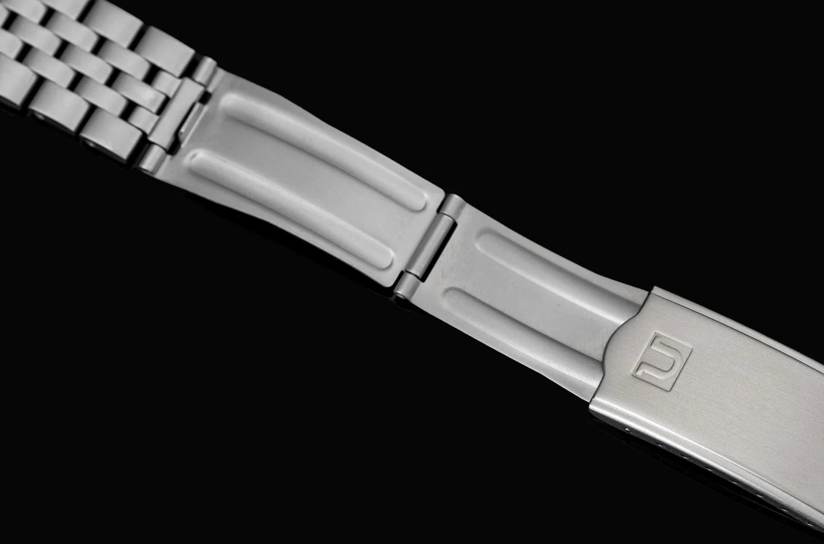 Silver stainless steel bracelet with mechanical watch end links and deployment clasp on black background