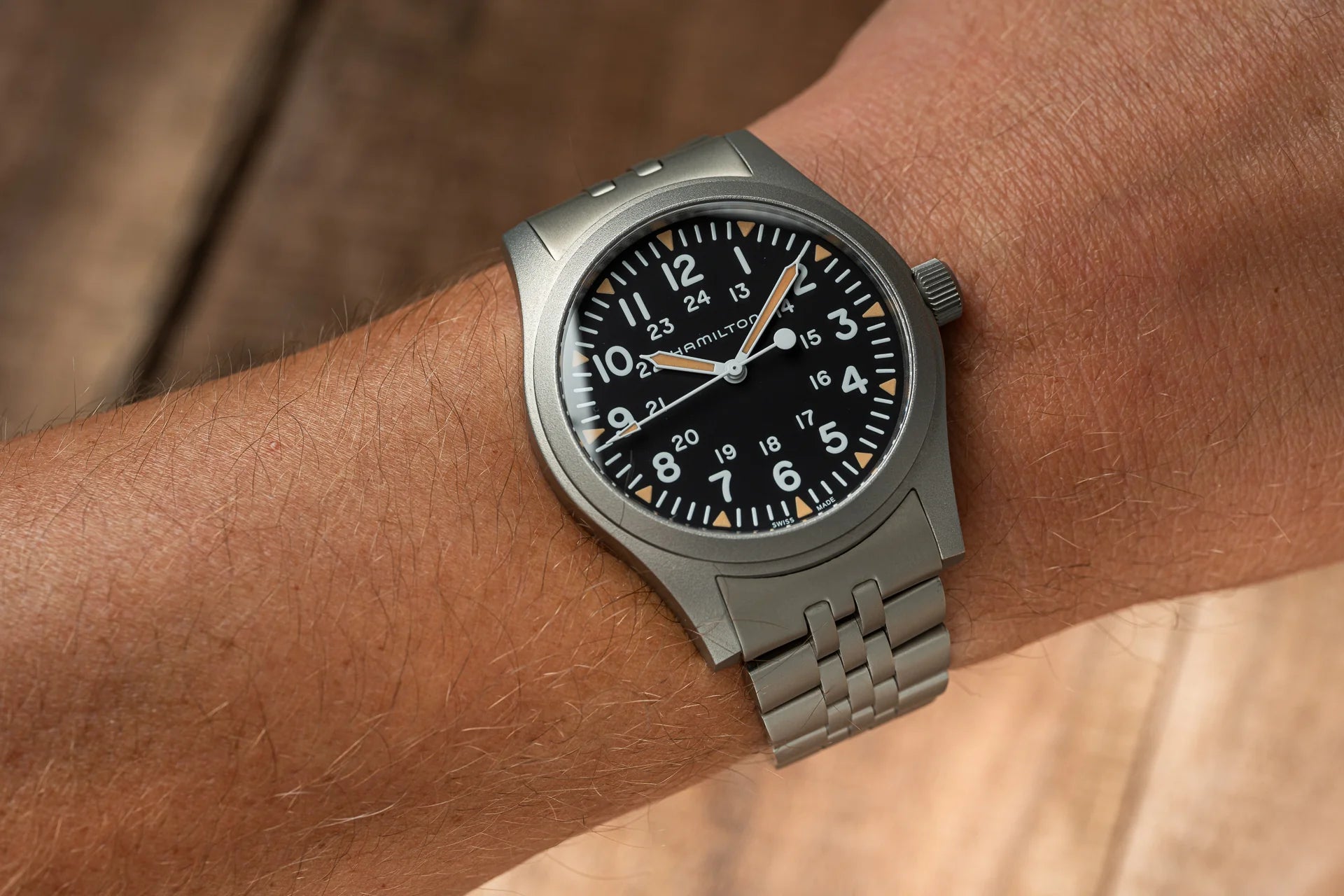 Hamilton Khaki mechanical watch with 42mm stainless steel case, black dial, orange hands, and matching metal bracelet worn on wrist