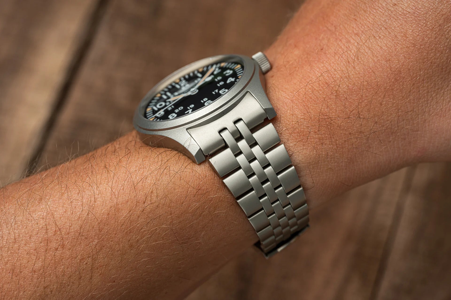Stainless steel mechanical watch with black dial and silver metal bracelet worn on wrist