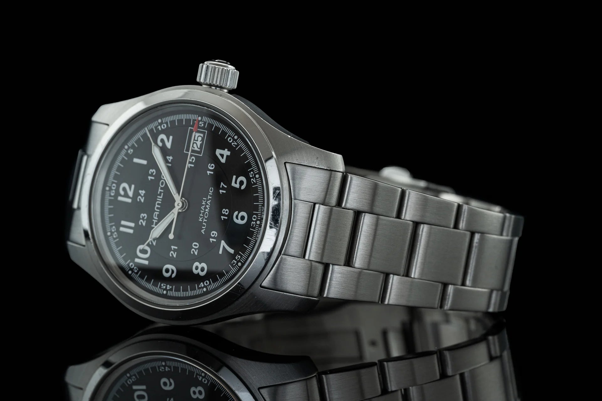Stainless steel automatic watch with black dial, Arabic numerals, date window, and integrated metal bracelet on black background