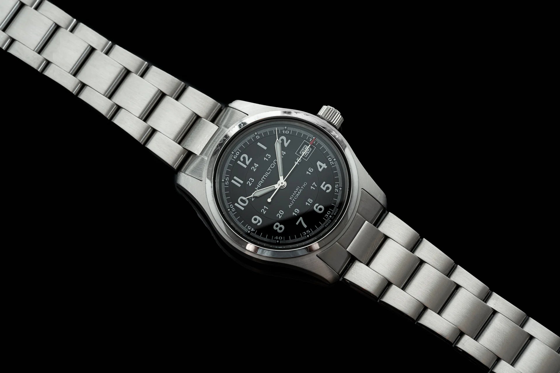 Stainless steel automatic watch with black dial and metal bracelet on black background