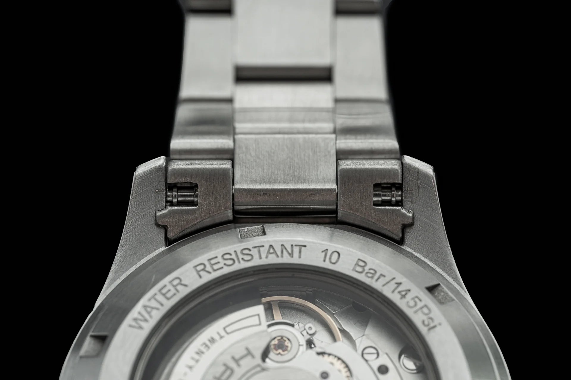 Stainless steel automatic watch with metal bracelet, water resistant 10 bar, showing exposed caseback with visible movement mechanism
