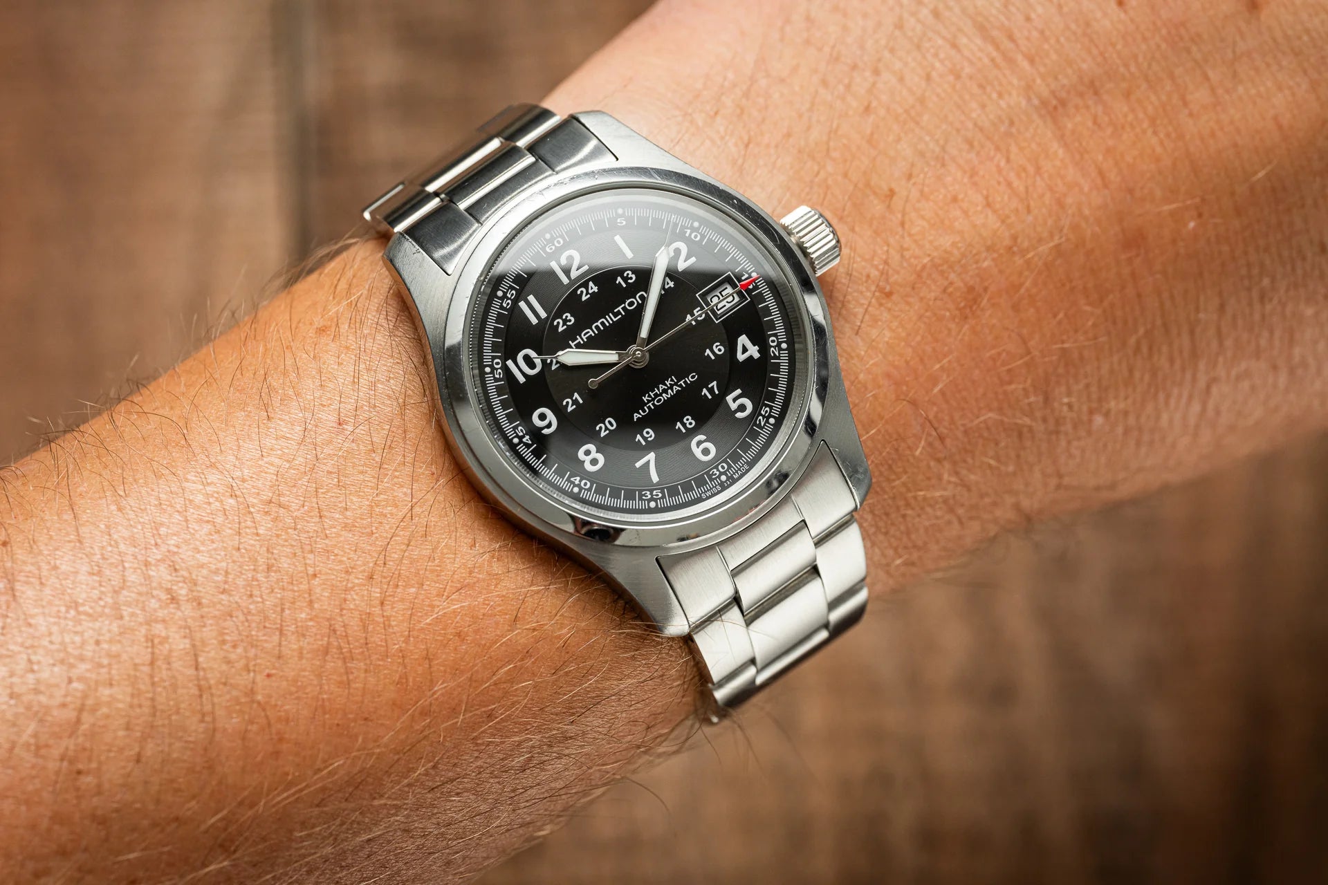 Hamilton Khaki Field automatic watch with black dial and stainless steel bracelet worn on wrist