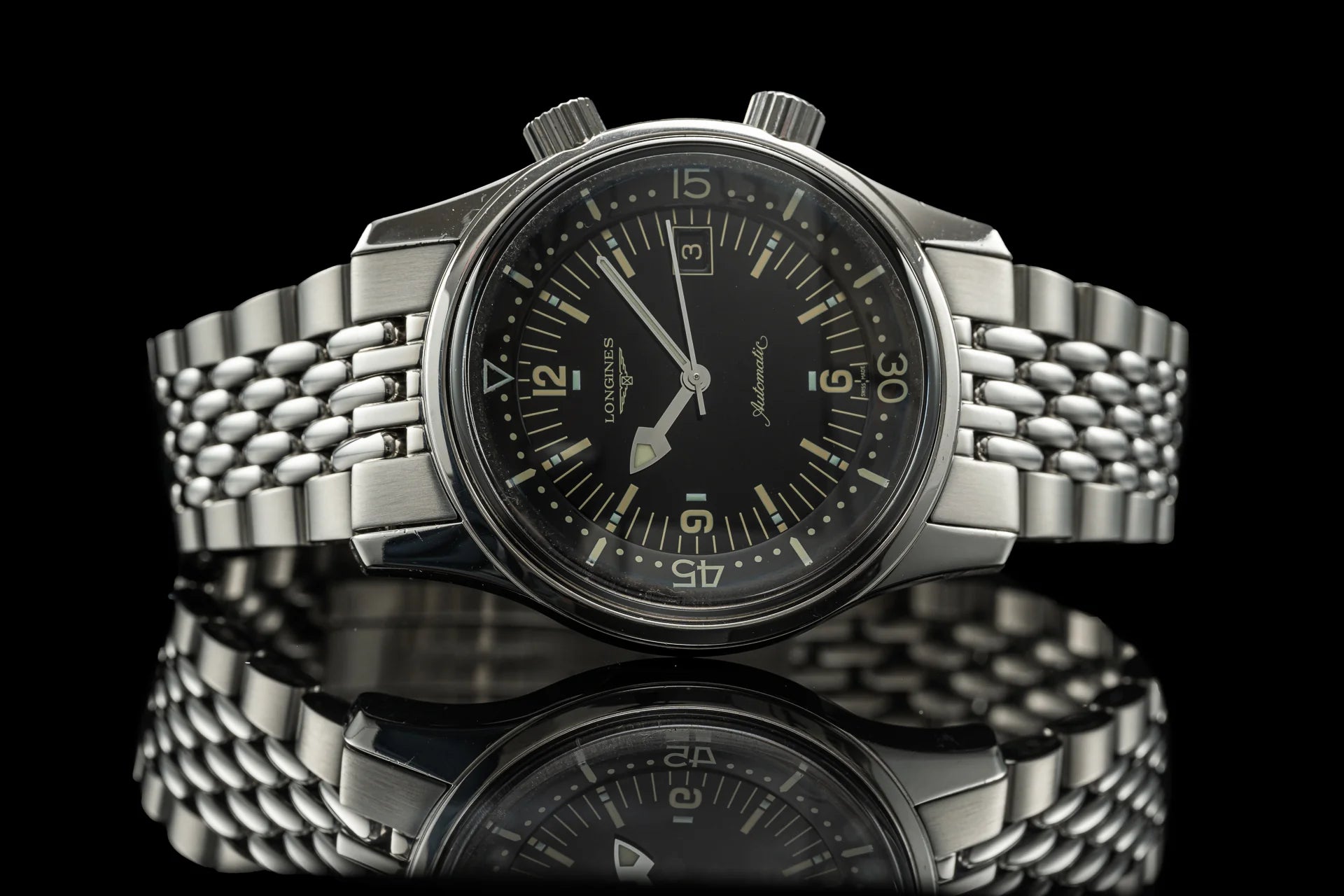 Longines Legend chronograph watch with black dial, stainless steel Beads of Rice bracelet, and luminous hands on black background