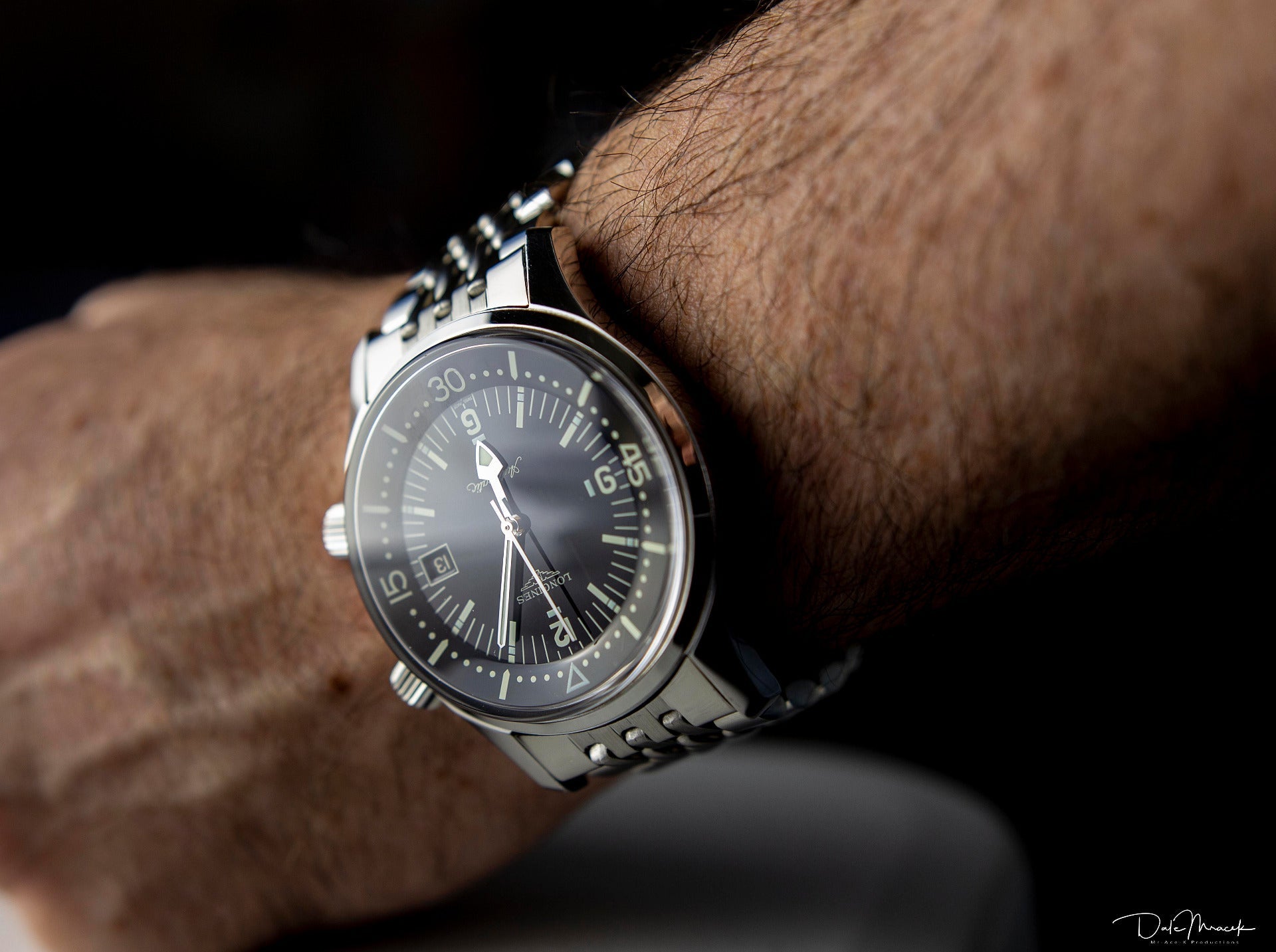Men's stainless steel watch with black dial and silver hands worn on wrist, featuring beaded metal bracelet and date window