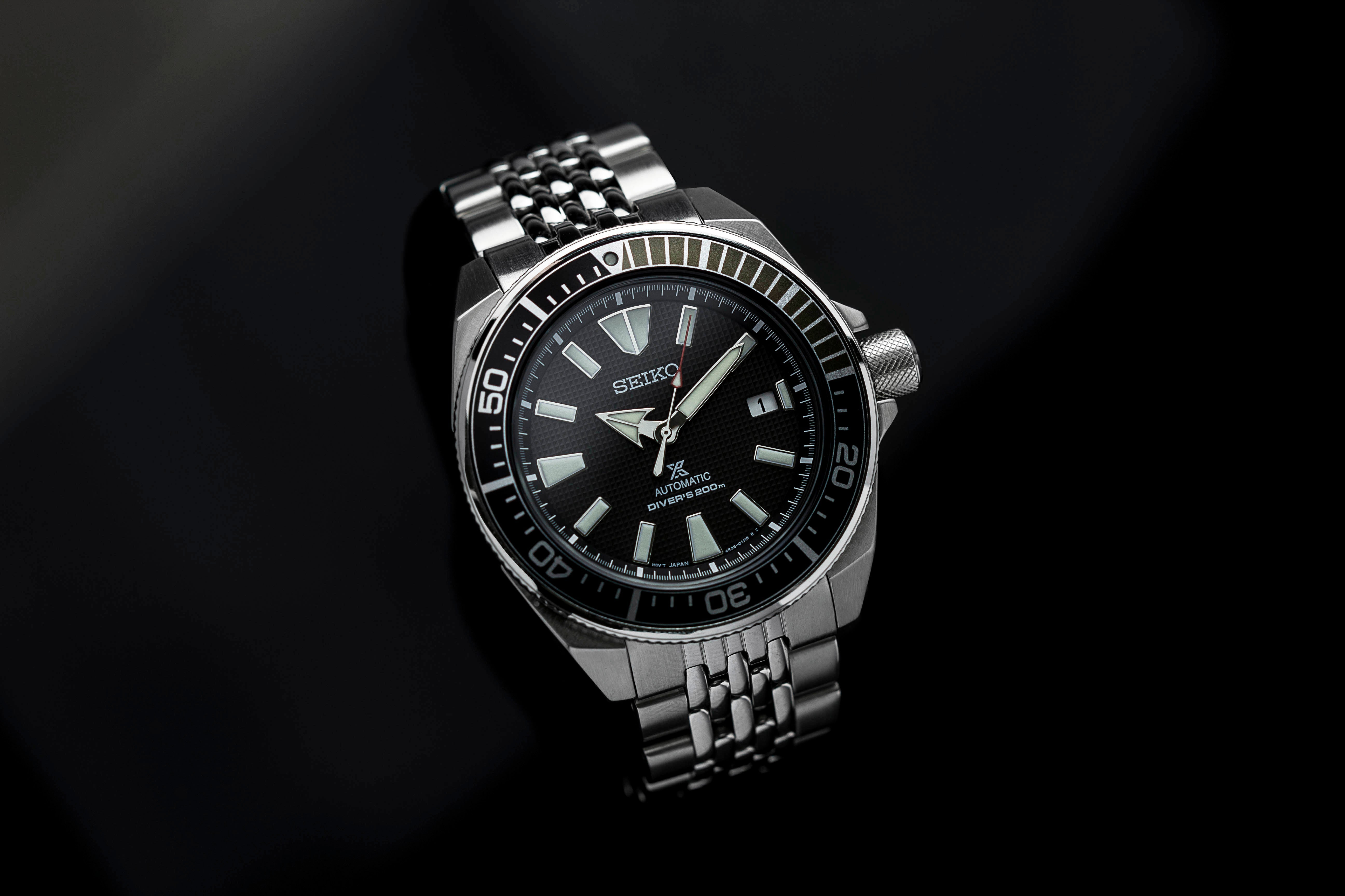 Seiko Samurai automatic dive watch with stainless steel bracelet and black dial on dark background