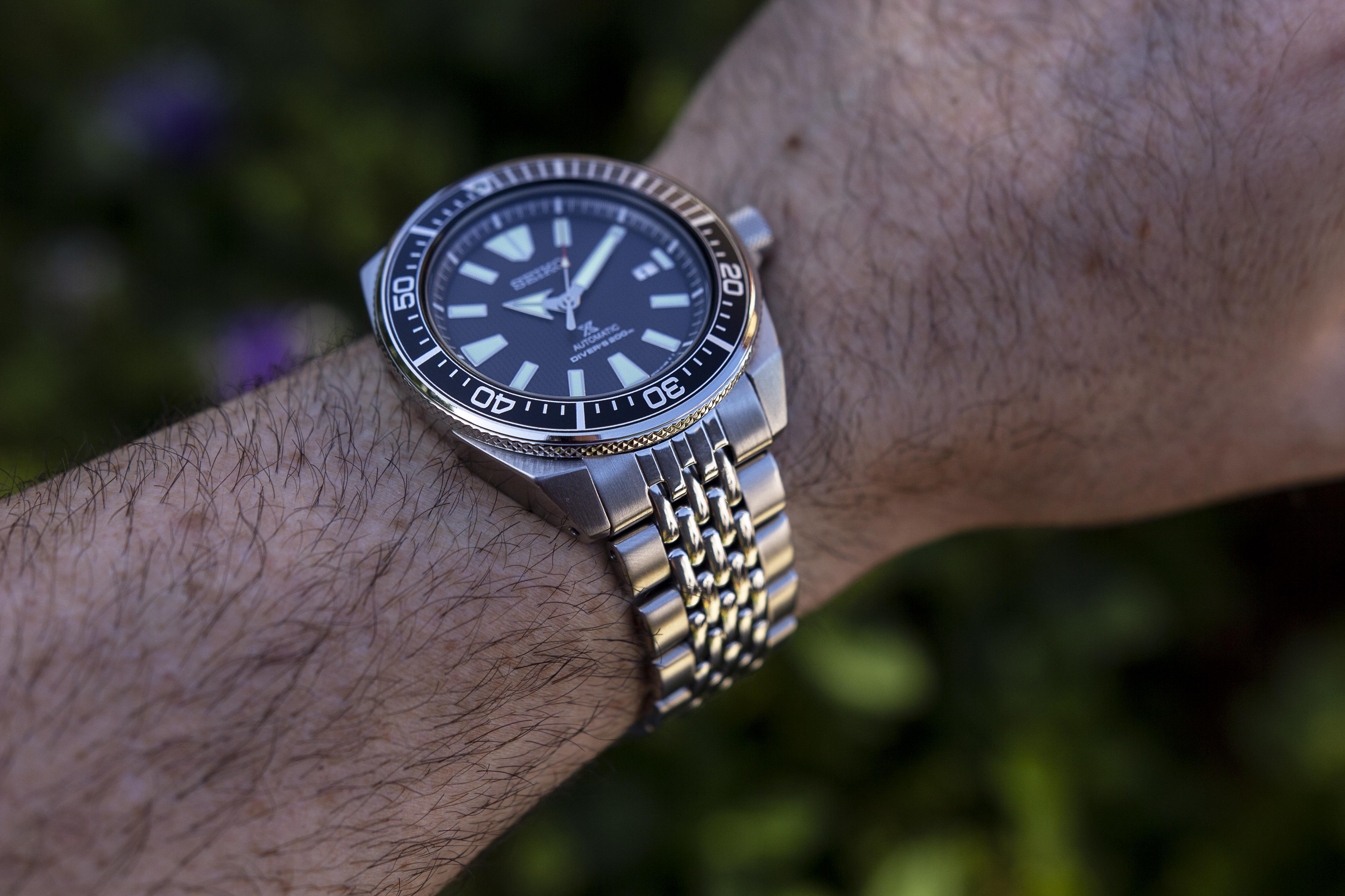 Seiko Samurai automatic dive watch with steel beads of rice bracelet worn on wrist, featuring black dial and rotating bezel
