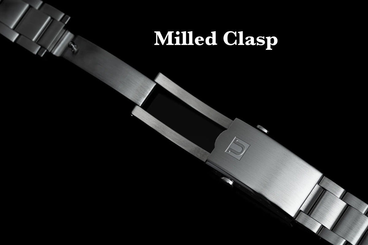 Brushed stainless steel milled clasp with polished center link on watch bracelet, top-down view