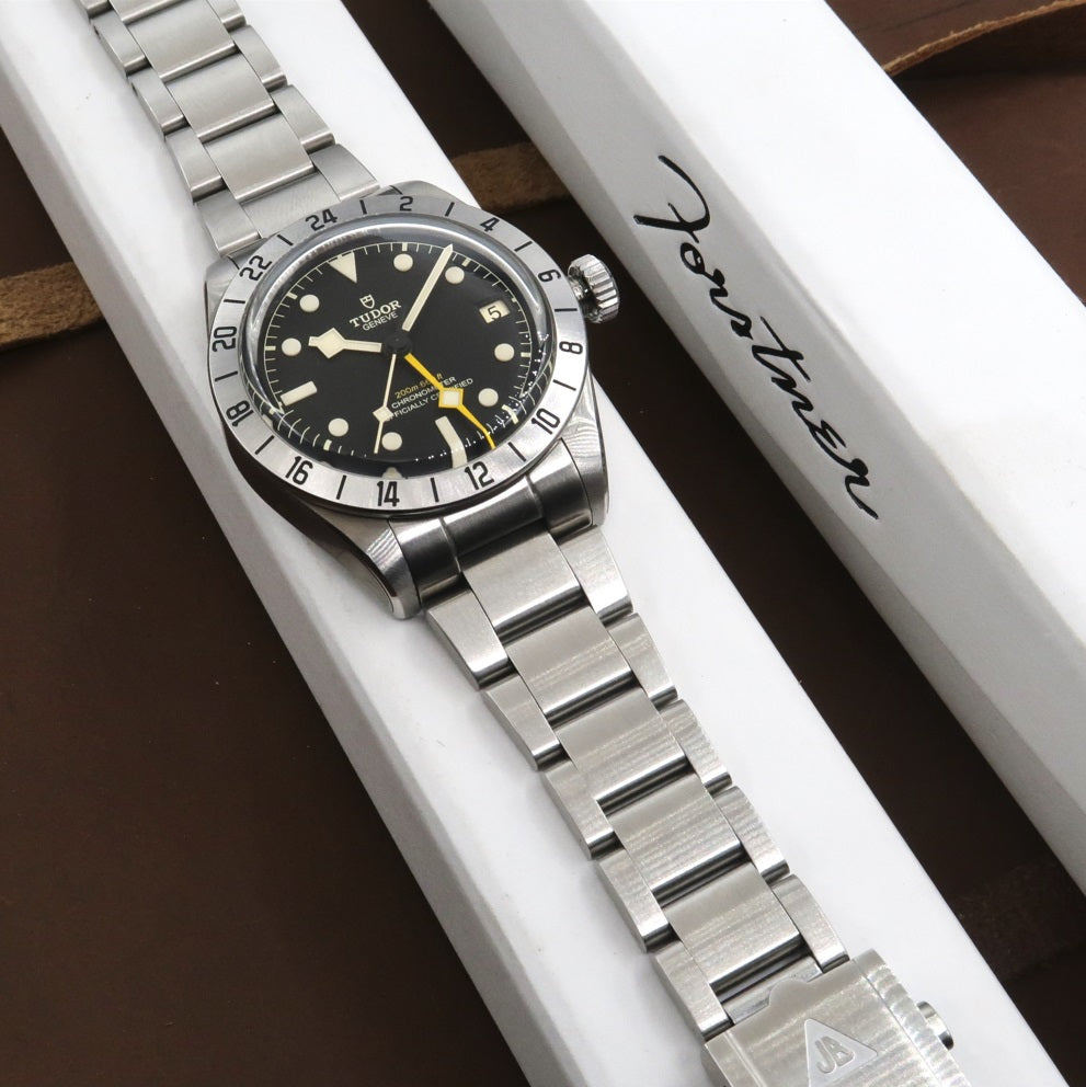 Tudor Black Bay Pro stainless steel diving watch with black dial, yellow hand, and GMT bezel on presentation box