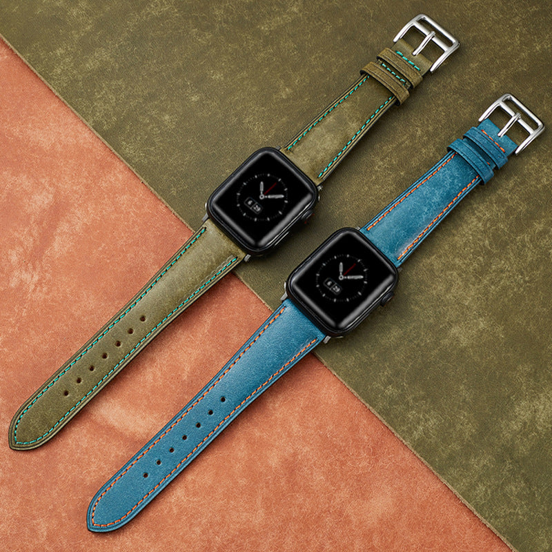 Two smartwatches with black cases featuring Italian leather bands in olive green and blue with contrasting stitching on color-blocked background