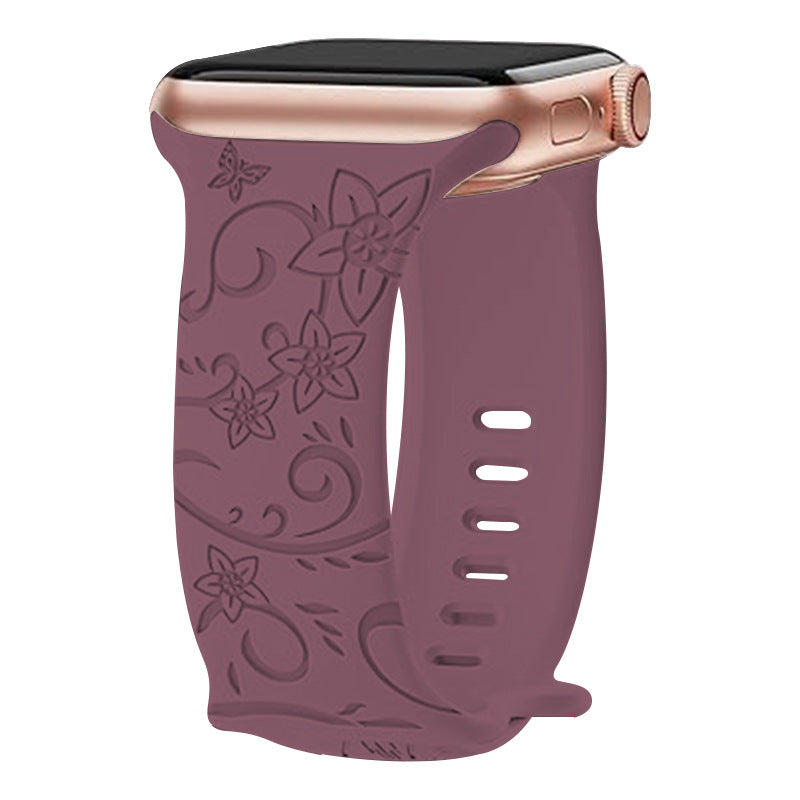 Rose gold Apple Watch with burgundy silicone band featuring floral vine embossed design and ventilation holes