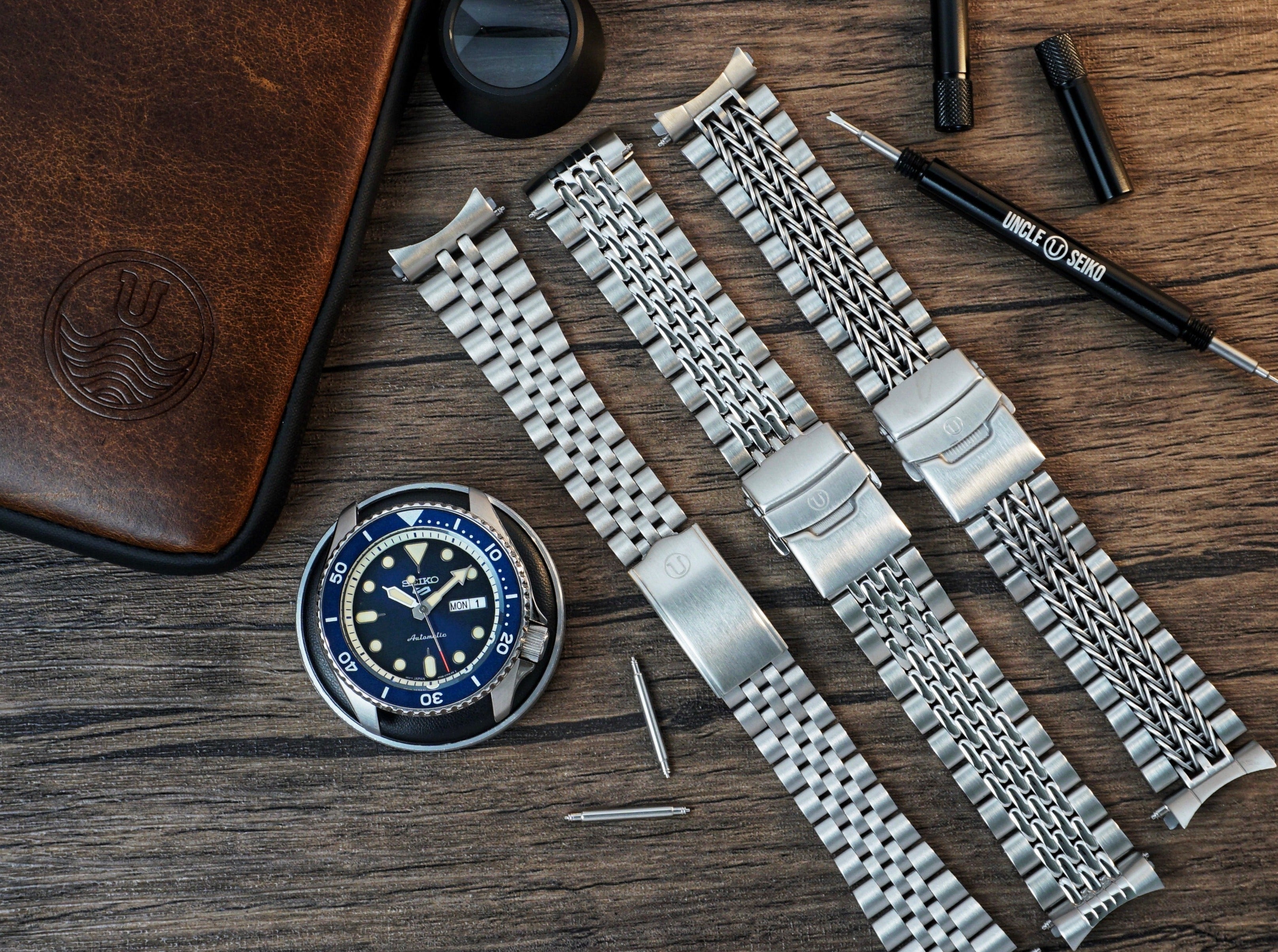 Stainless steel watch bracelets with razor-wire mesh design for Seiko dive watches, displayed with tools and leather watch case