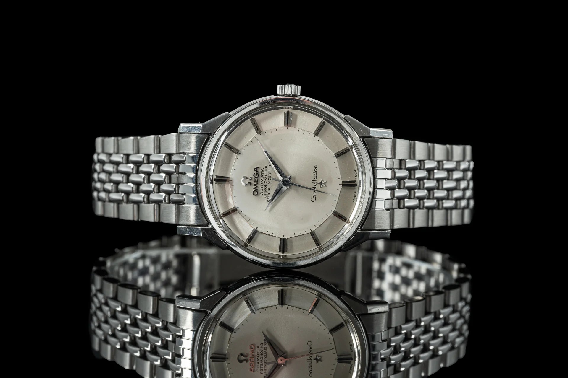 Vintage Omega Constellation stainless steel watches with silver dial and beads of rice bracelet on black background