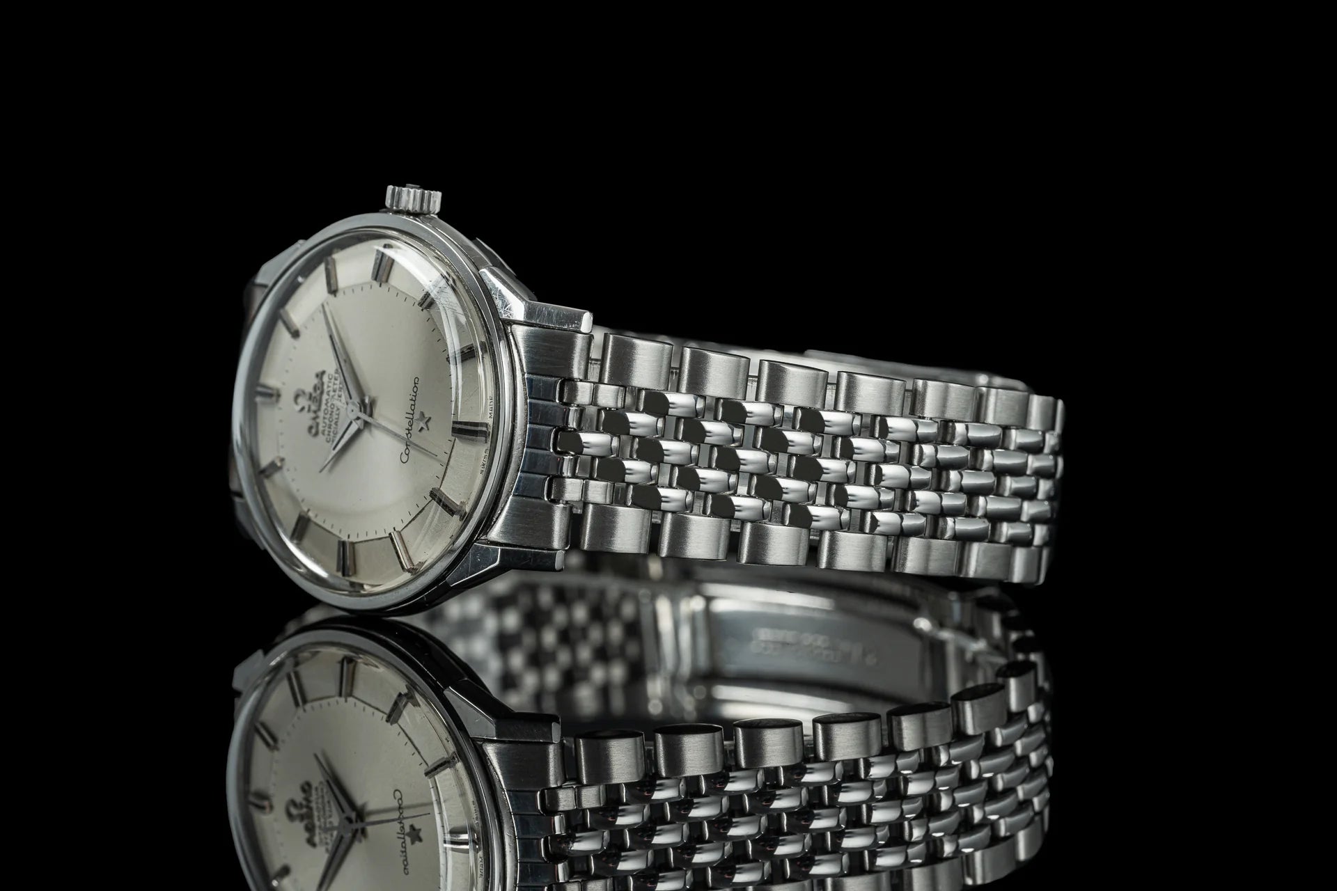 Vintage Omega Constellation stainless steel watch with silver dial and beads of rice bracelet on black background