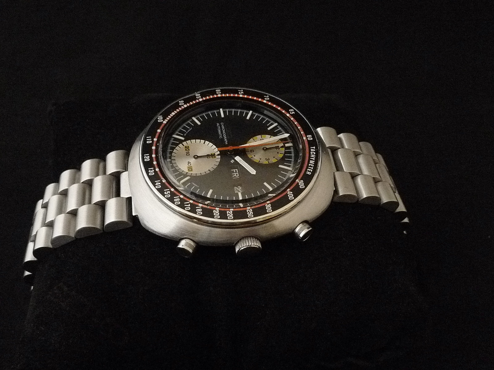 Vintage Seiko 6138 chronograph watch with stainless steel bracelet, black dial, and cream subdials on black background