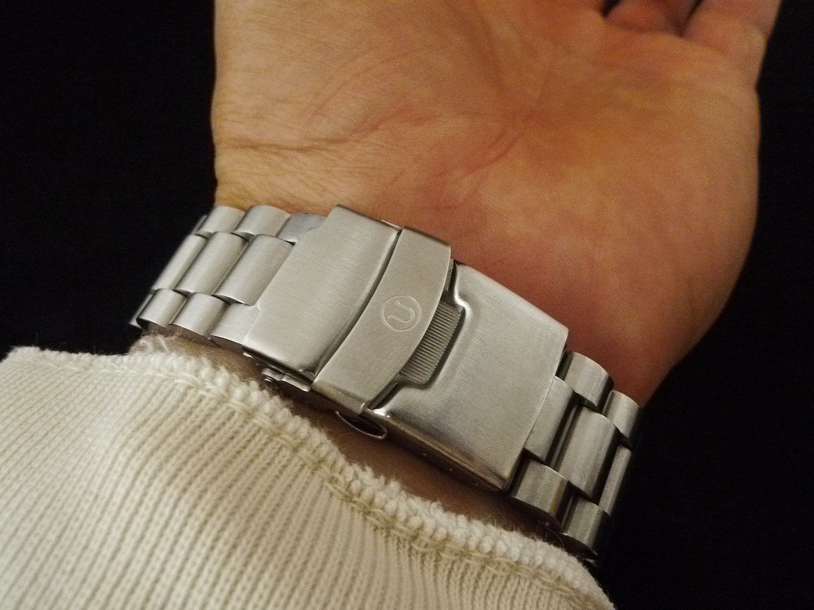 Stainless steel three-link bracelet watch worn on wrist, showing brushed metal finish and secure clasp closure
