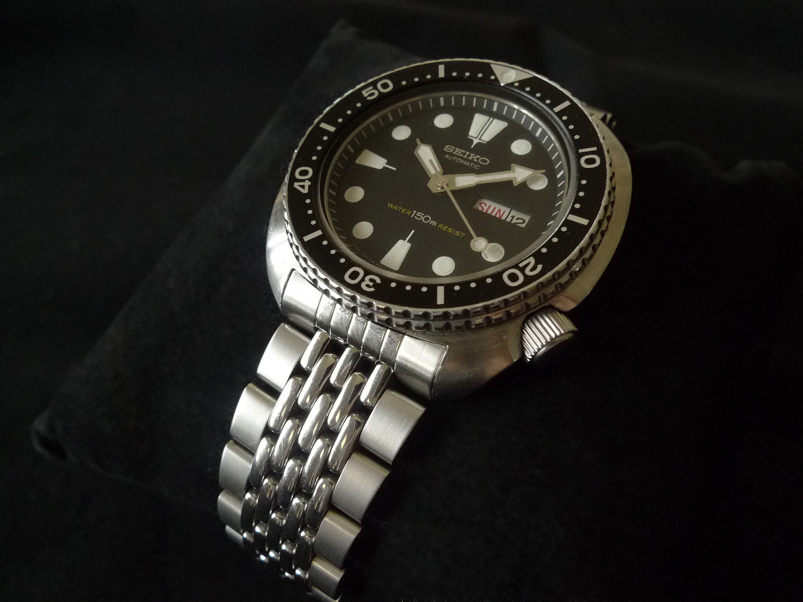 Seiko 6309 automatic dive watch with stainless steel beads of rice bracelet, black dial, day-date window, and 150m water resistance