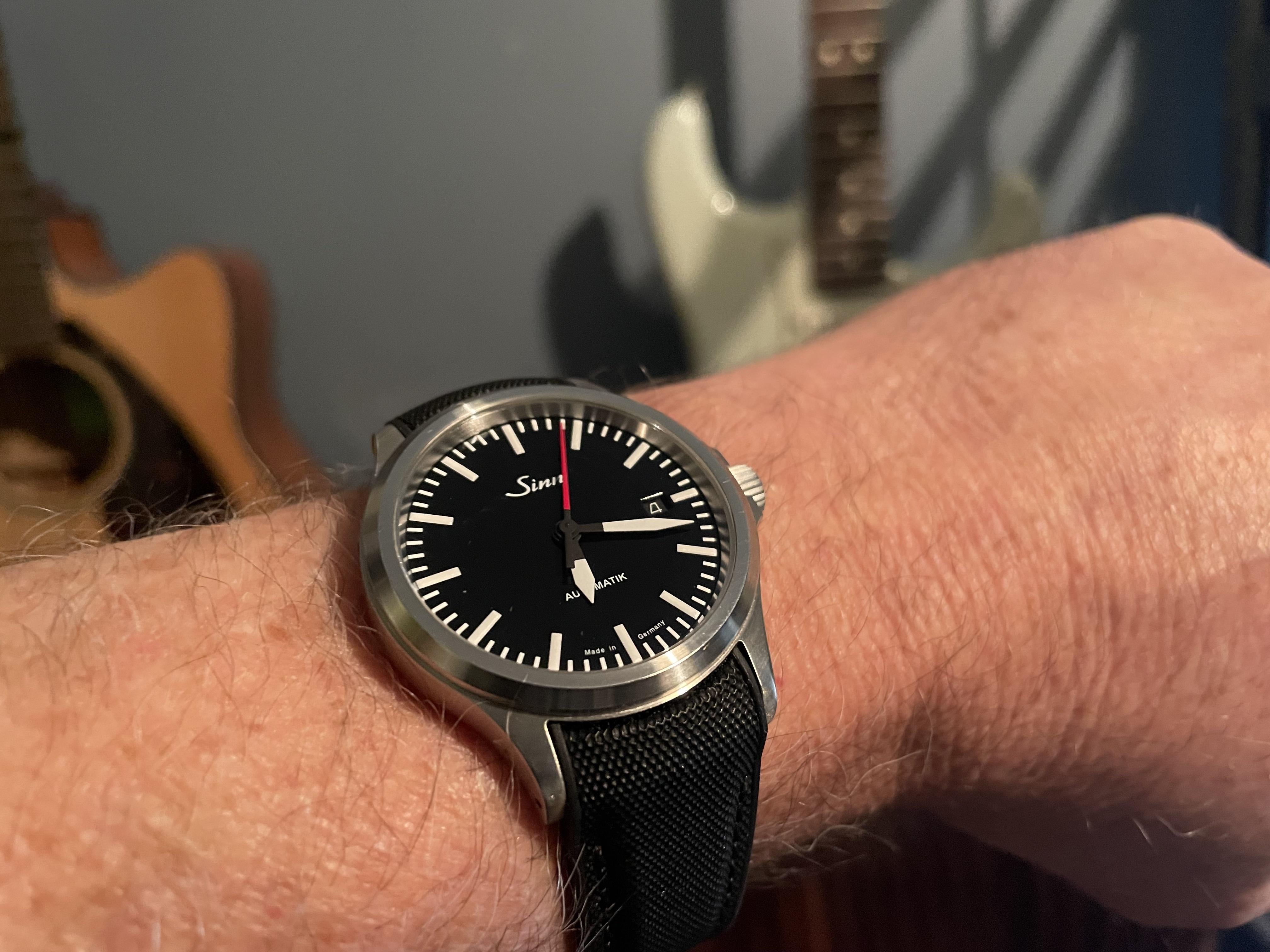Sinn automatic watch with black dial and steel case worn on wrist with black rubber strap and deployant clasp
