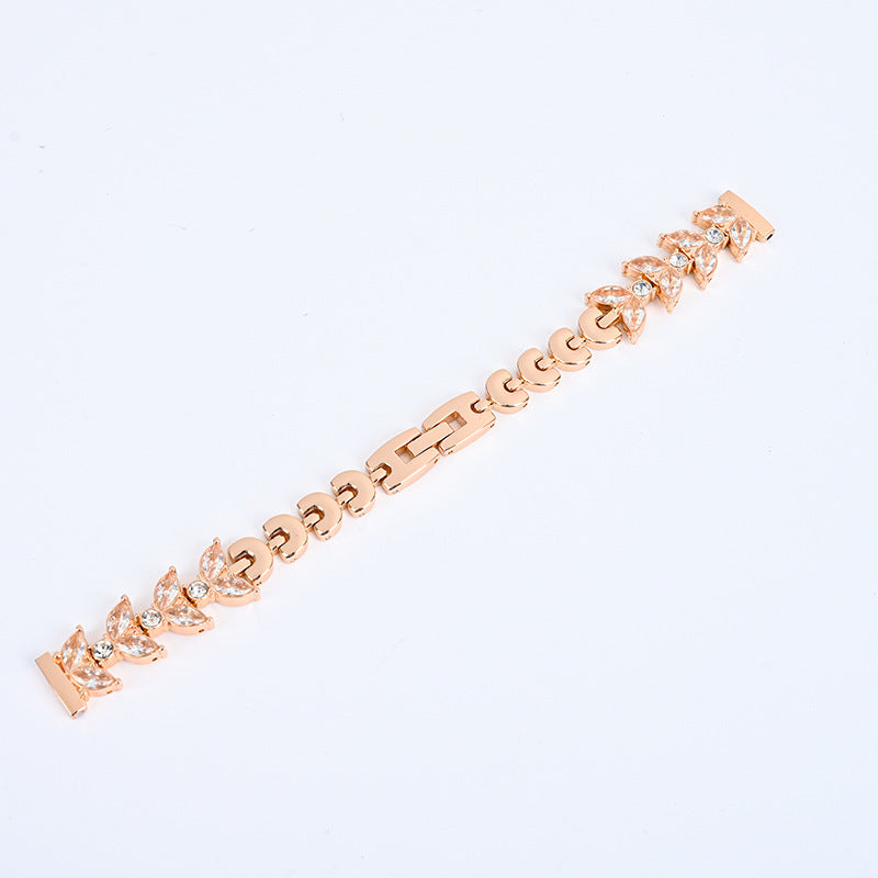 Rose gold tennis bracelet with cubic zirconia leaf and round crystal designs on white background