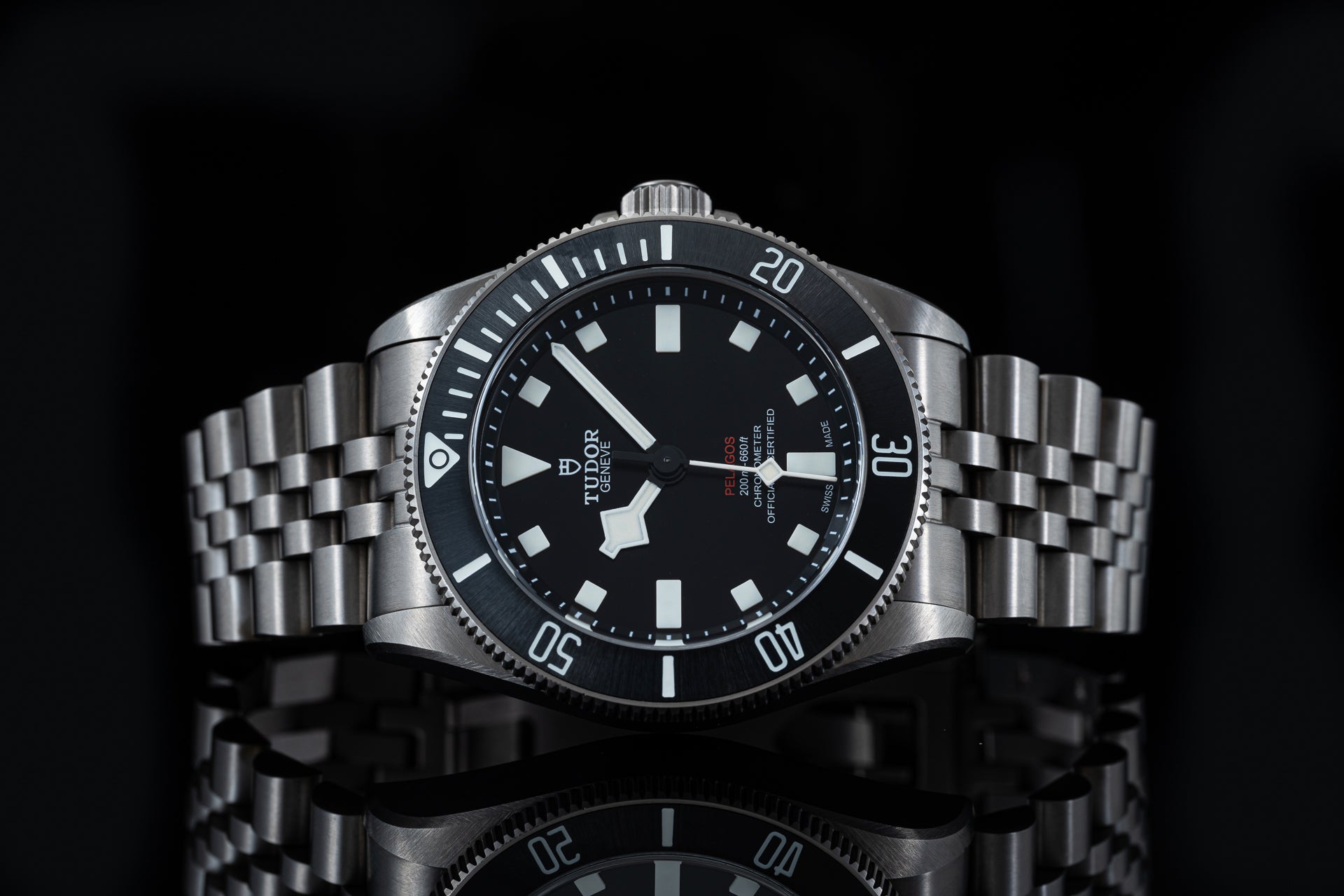 Stainless steel dive watch with black dial, rotating bezel, and integrated bracelet on black background