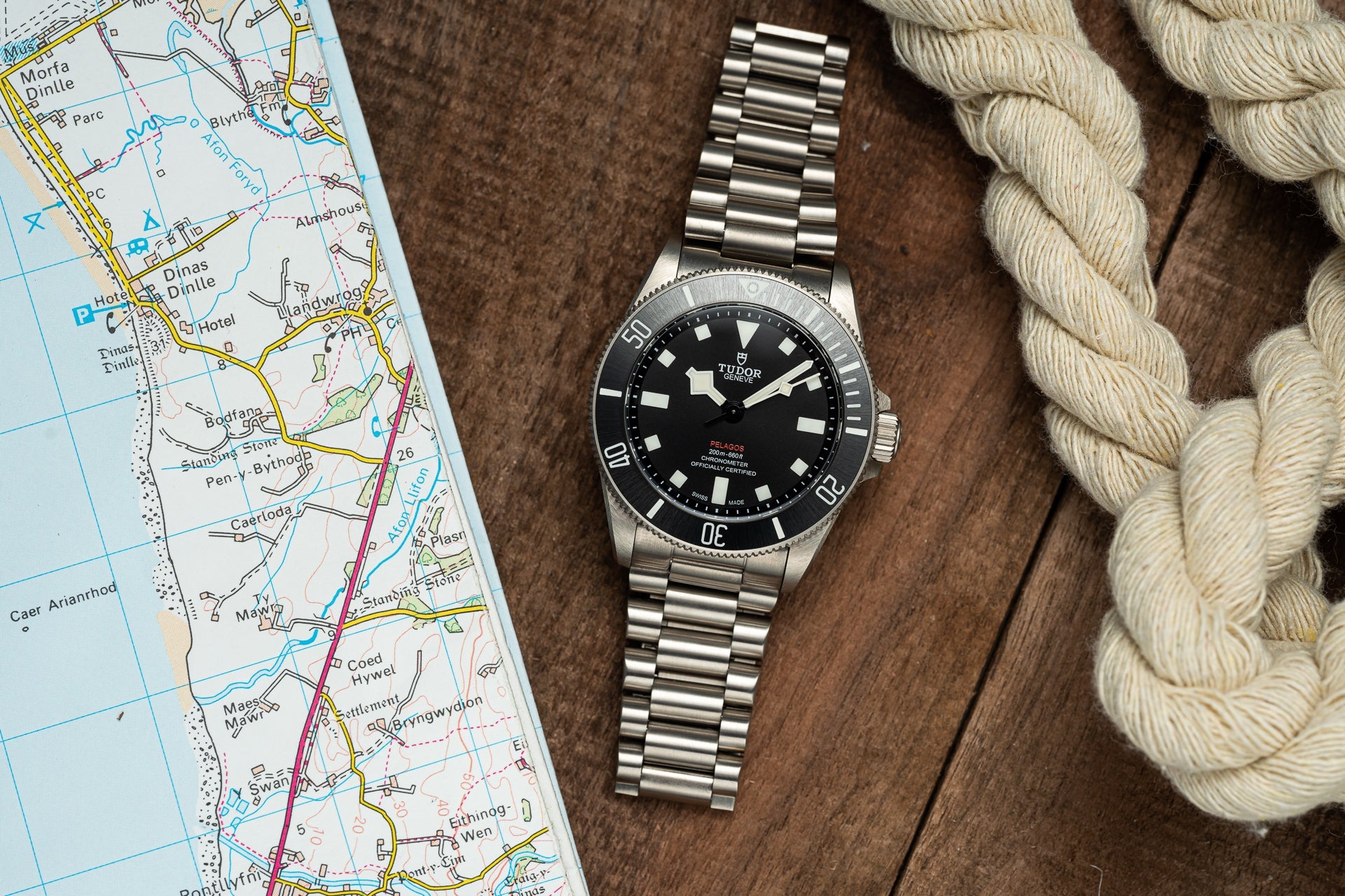 Tudor Pelagos 39mm dive watch with black dial and stainless steel bracelet on map and rope background