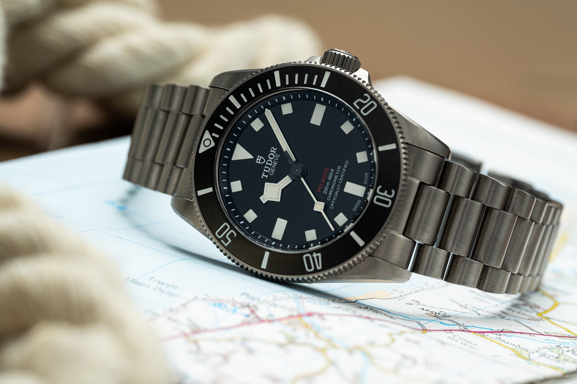 Tudor Pelagos 39mm titanium dive watch with black dial and square hour markers on matching titanium bracelet, displayed on navigation map