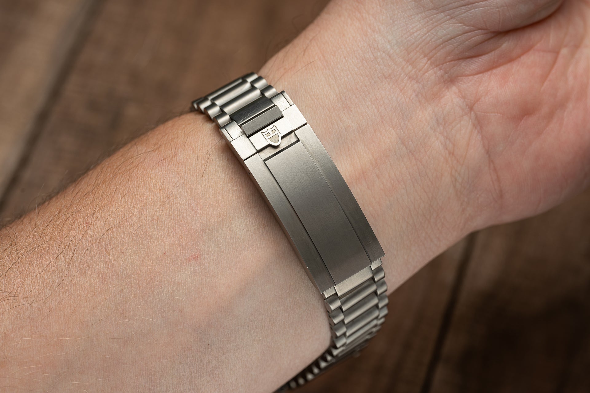 Brushed titanium bracelet with integrated end links worn on wrist, featuring sturdy metal link construction and push-button clasp closure