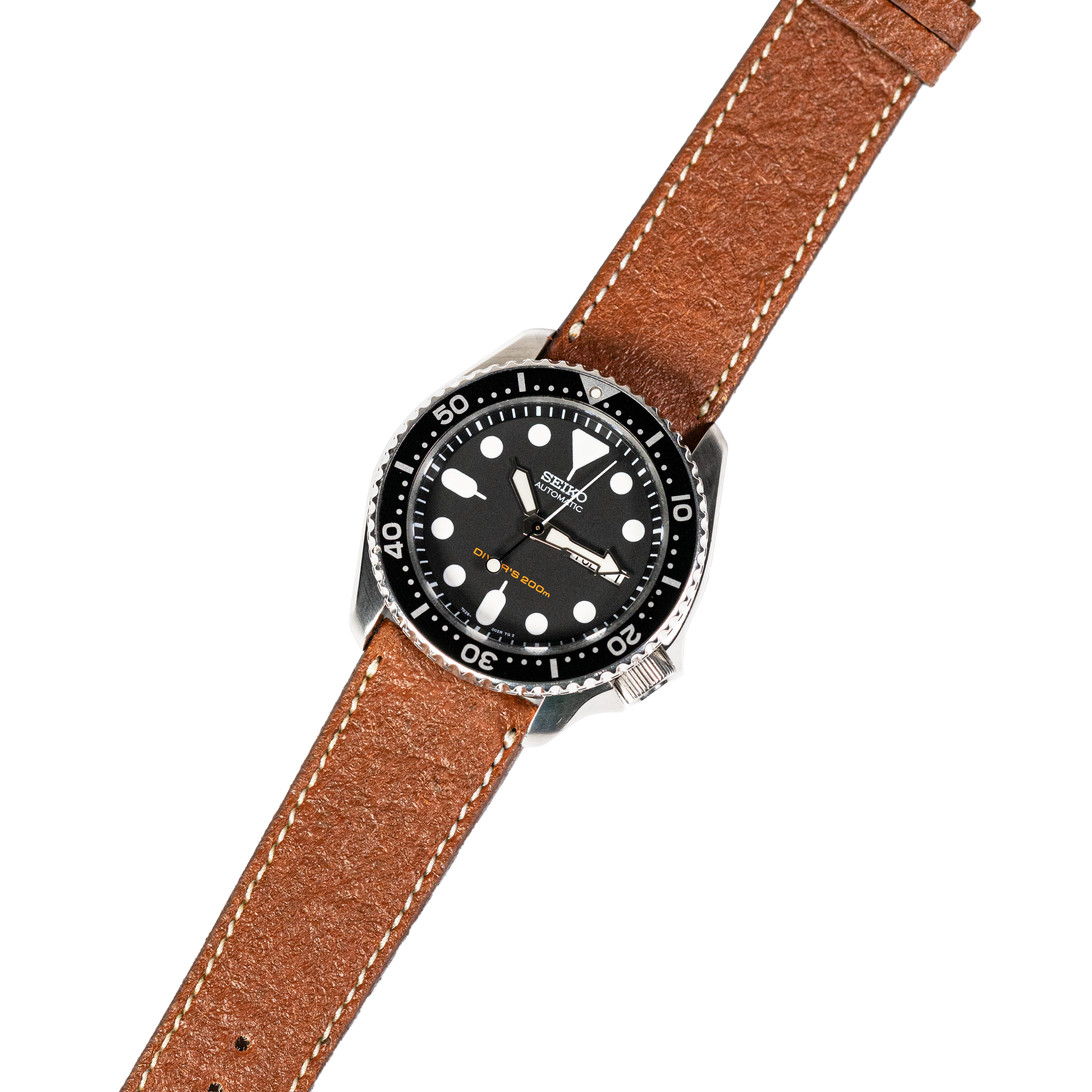 Seiko dive watch with black dial, white hour markers, rotating bezel, and tan leather strap with white stitching